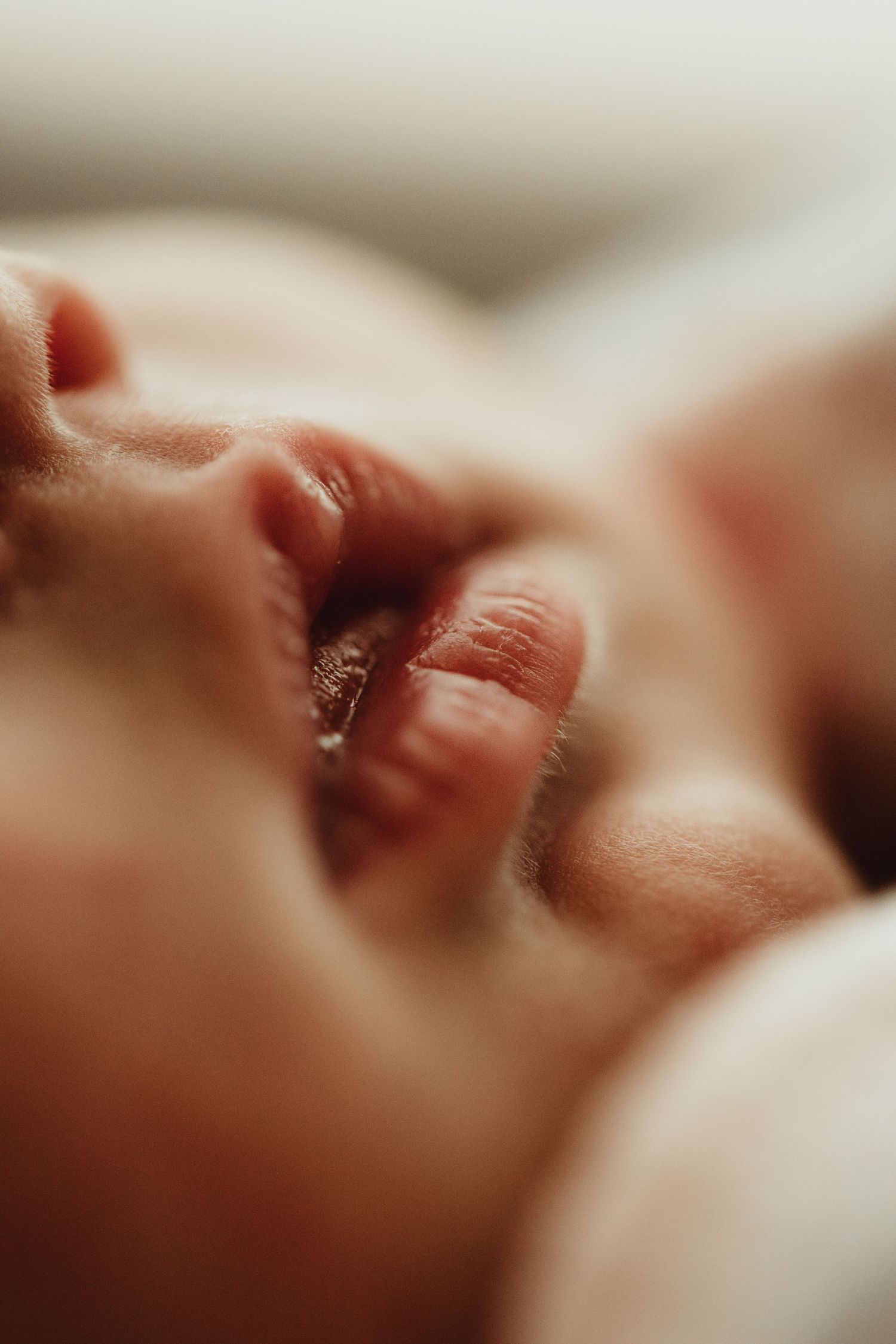 Close-up detail shot of tiny newborn baby fingers grasping in soft, warm lighting.