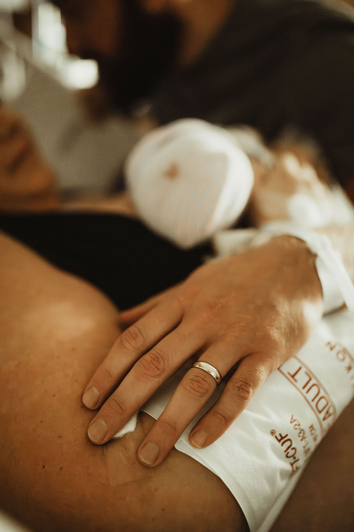 A close-up sequence showing a hand with a gold wedding band resting on white fabric.