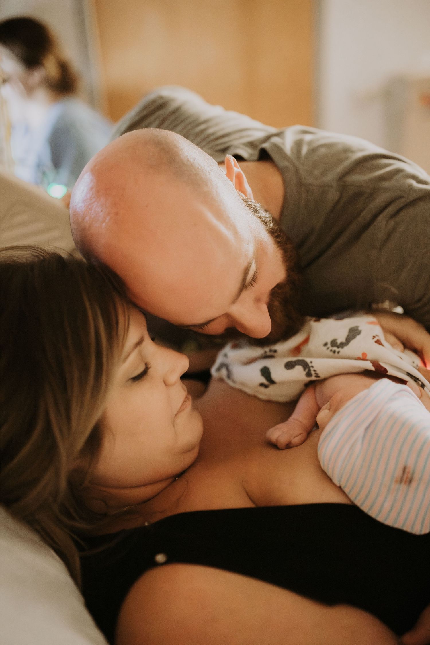 Parent and baby resting together in peaceful embrace, creating tender moment of bonding in warm lighting.