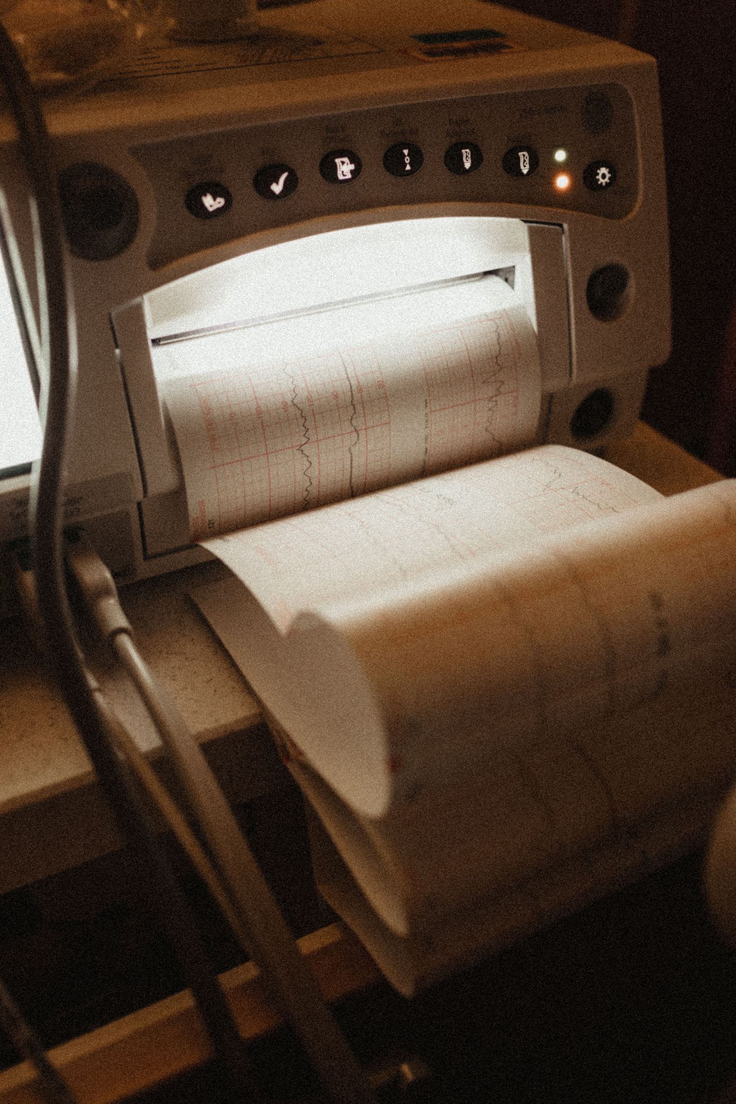 Industrial paper rolls on printing press machinery shown in sepia tones with dramatic lighting effects.