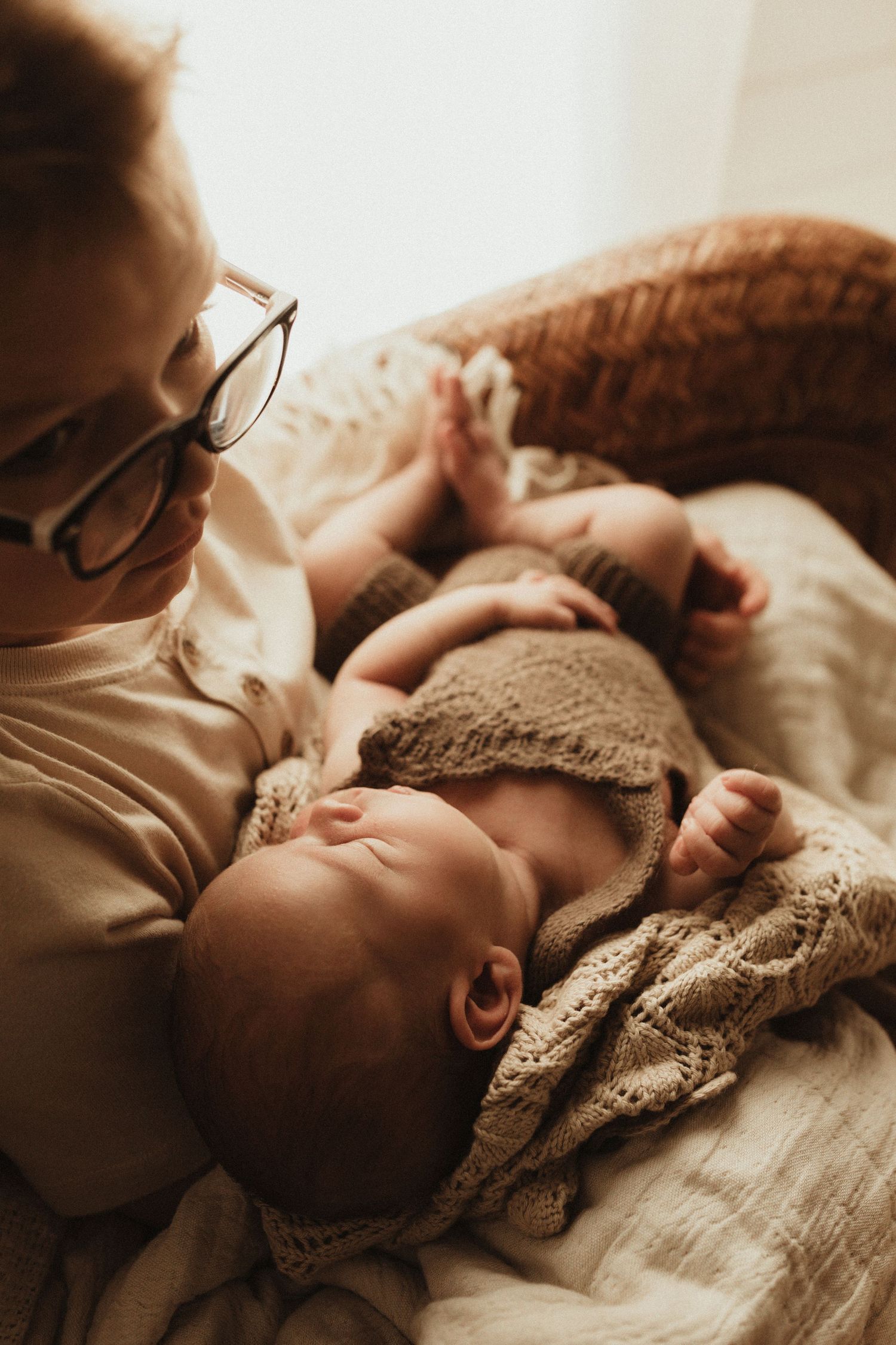 Sleeping baby wrapped in cozy knit blanket with gentle light streaming in from window.