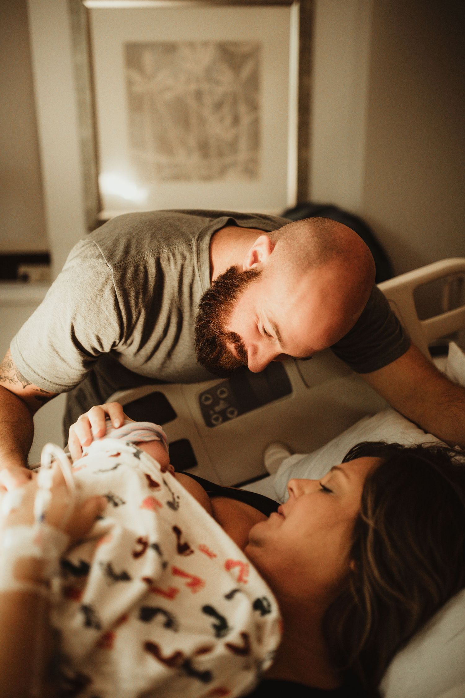 A couple shares an intimate moment lying together on the bed in a soft, warm light.