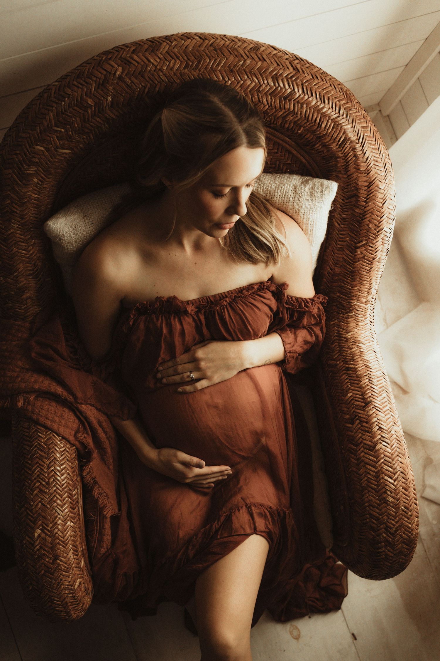 A figure in a rustic red dress reclines on a woven wicker chair in an artistic sequential photo series.