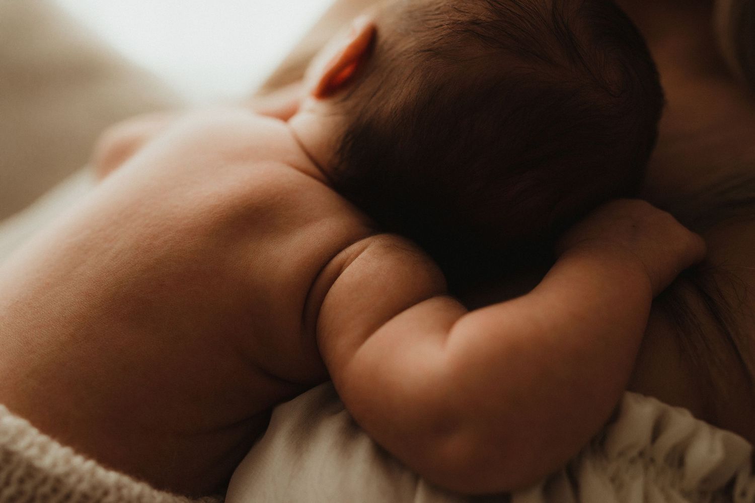 Close-up photo of baby feet against a warm golden-lit background during sunset.