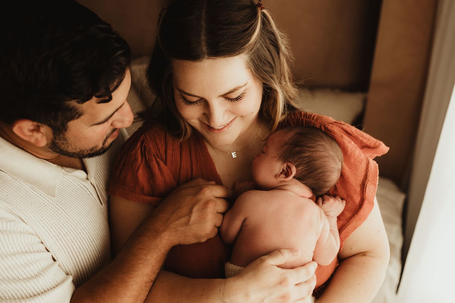 Intimate family moment with newborn baby in warm indoor lighting.