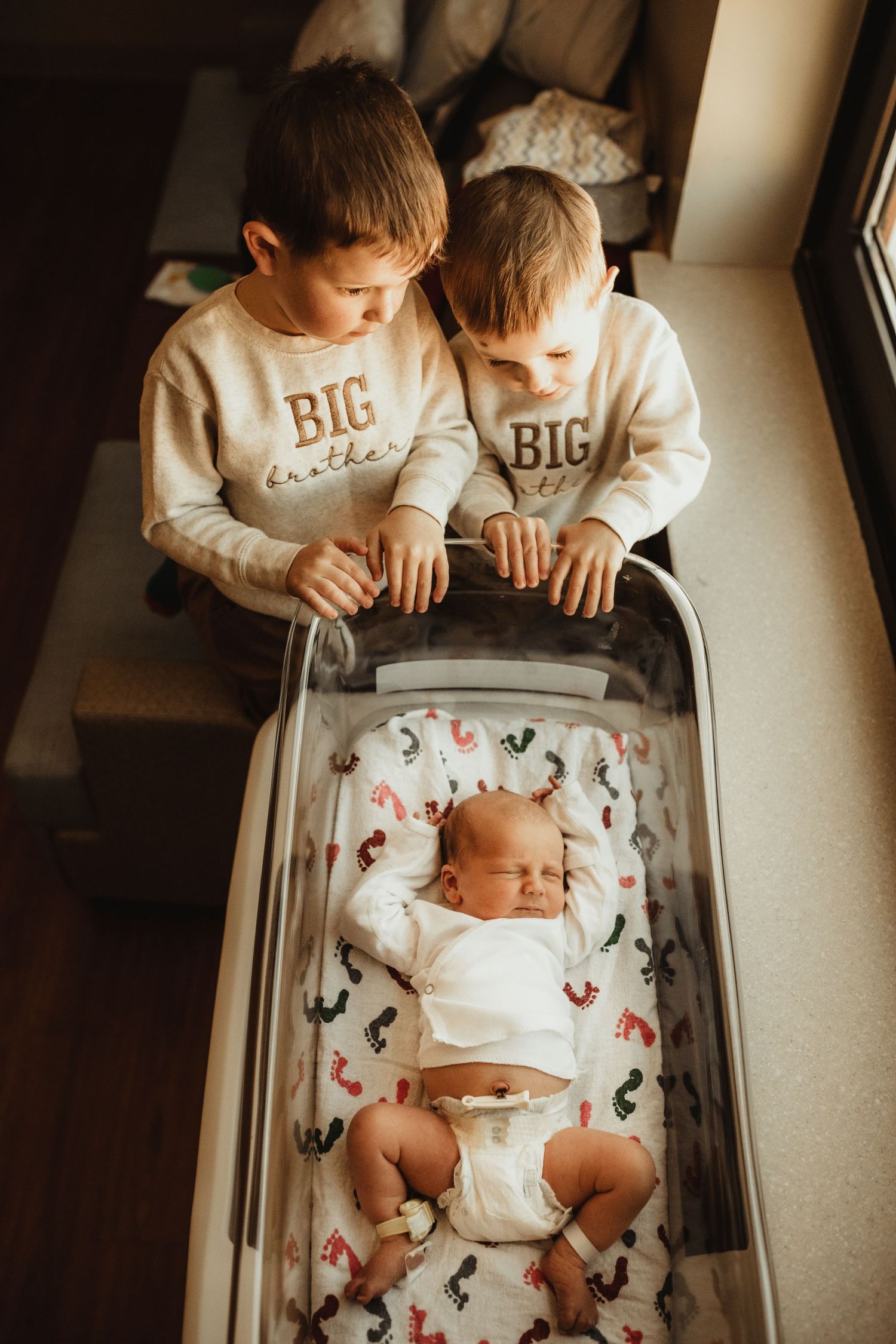 A baby lies peacefully in a crib with butterfly patterned bedding while others watch from above.