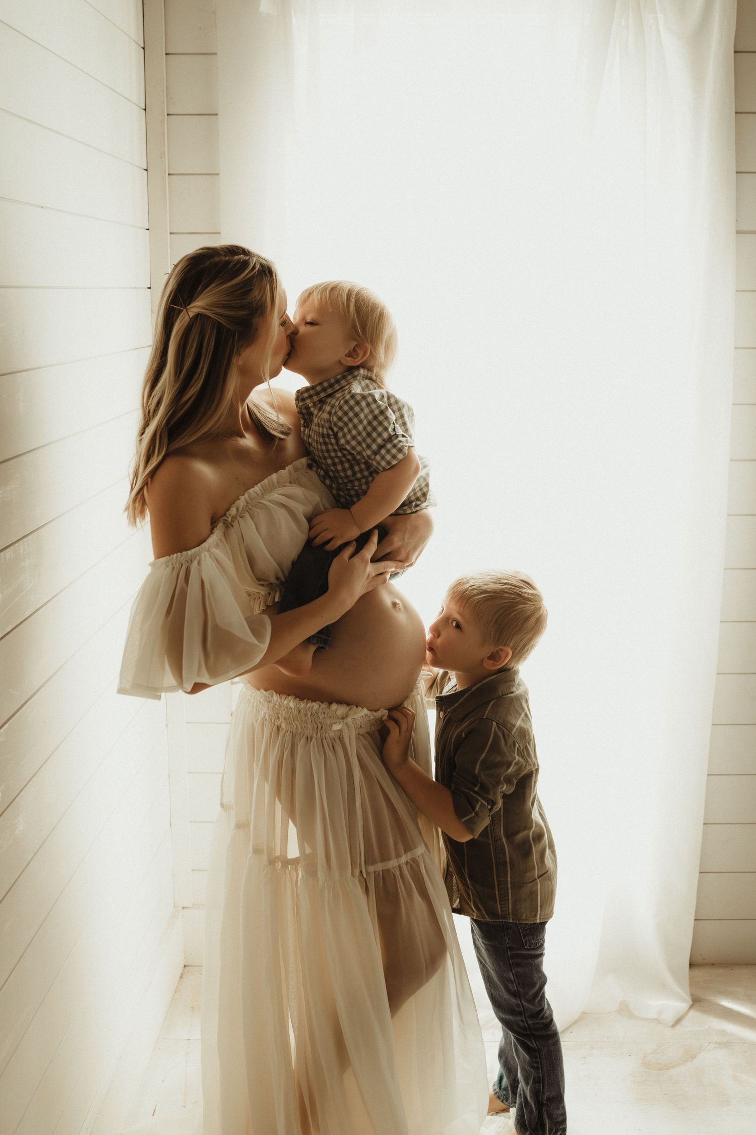 Series of intimate window-lit family moments showing soft embraces between mother and children in white flowy dress.