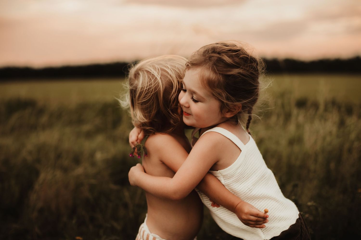 A tender, silhouetted embrace between two people in a serene field during golden hour.