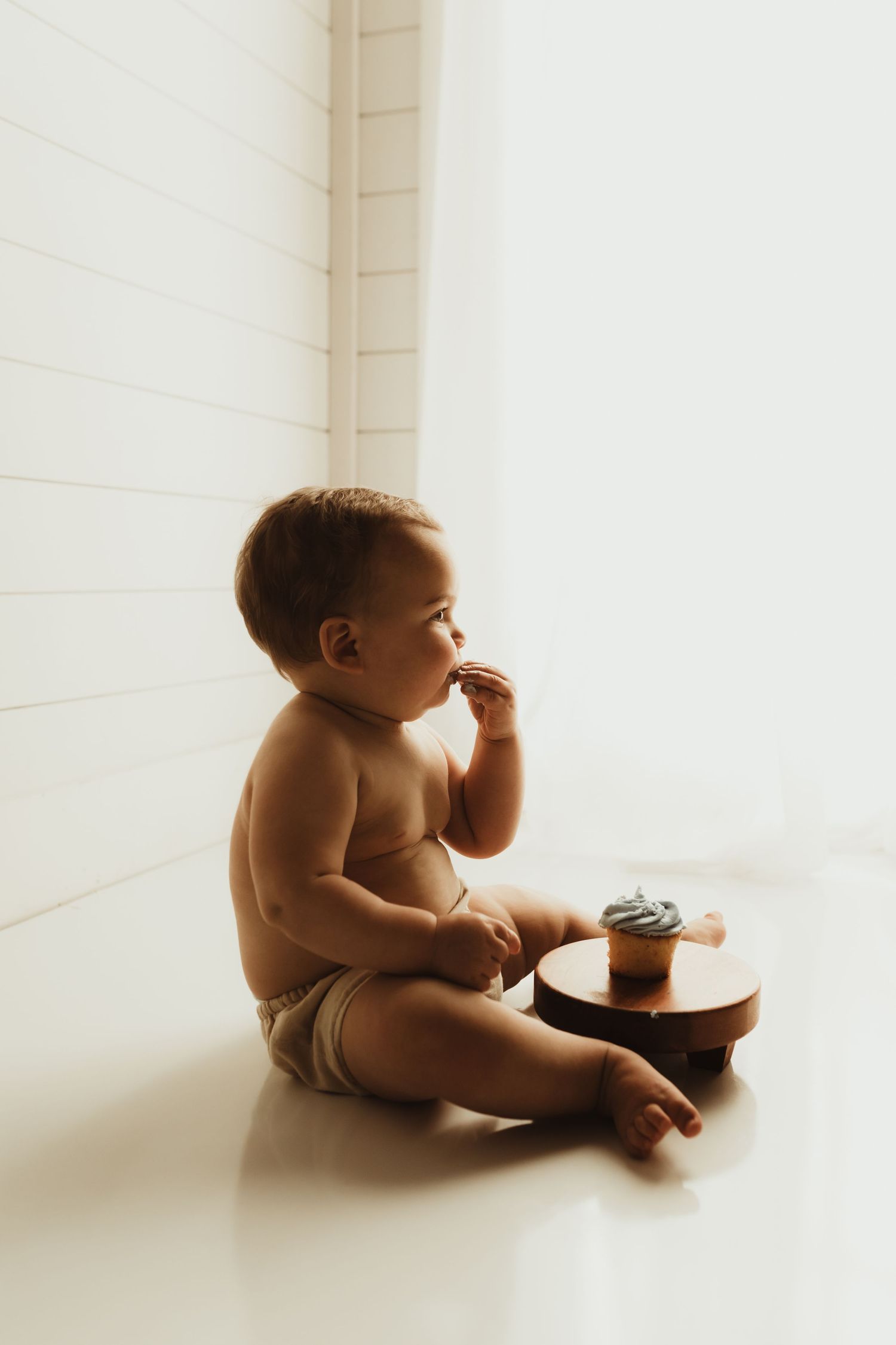 A baby in a diaper sits on a white floor in various poses creating a sequence of connected images.