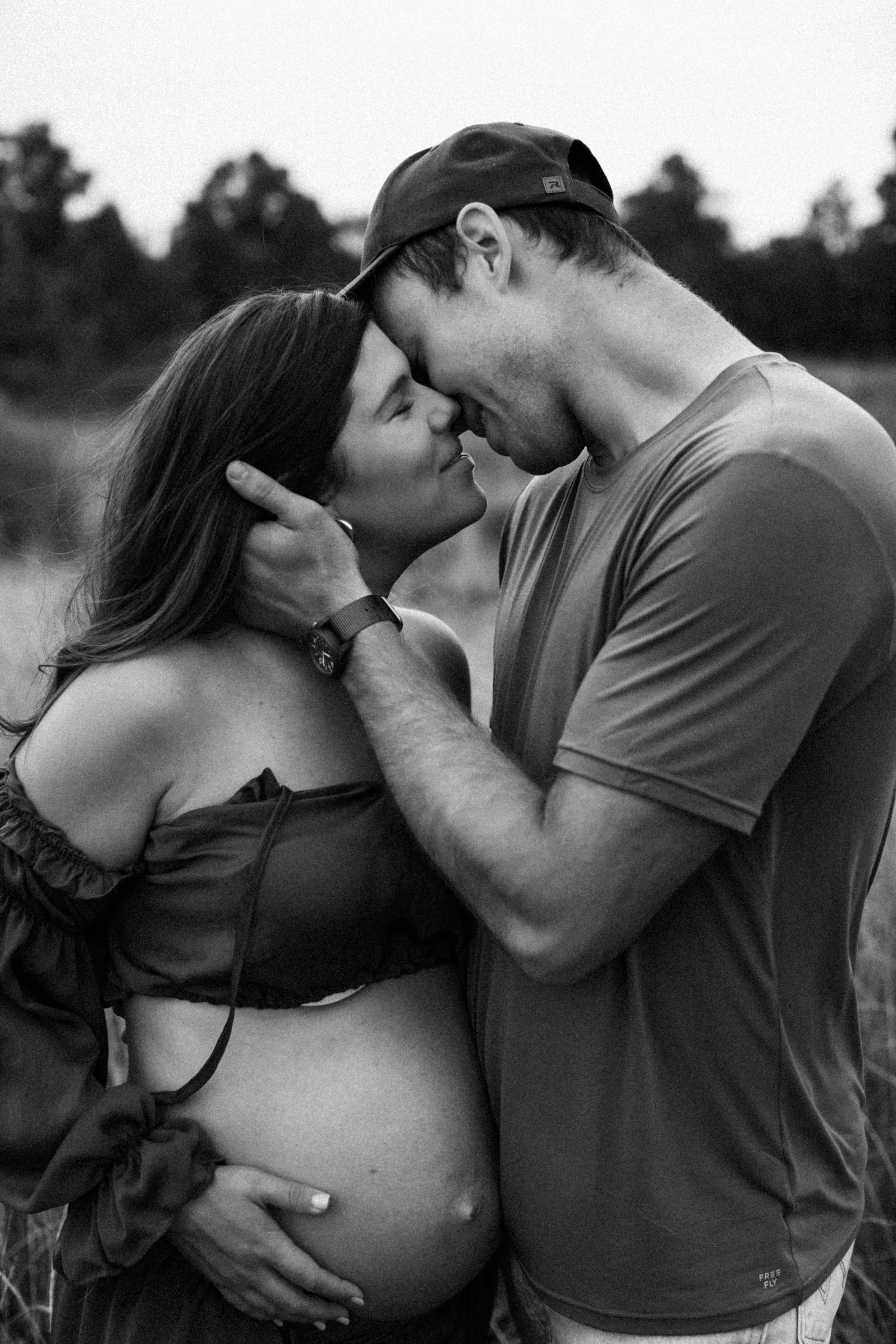 A series of black and white maternity photos showing intimate silhouettes of an expecting couple embracing outdoors.