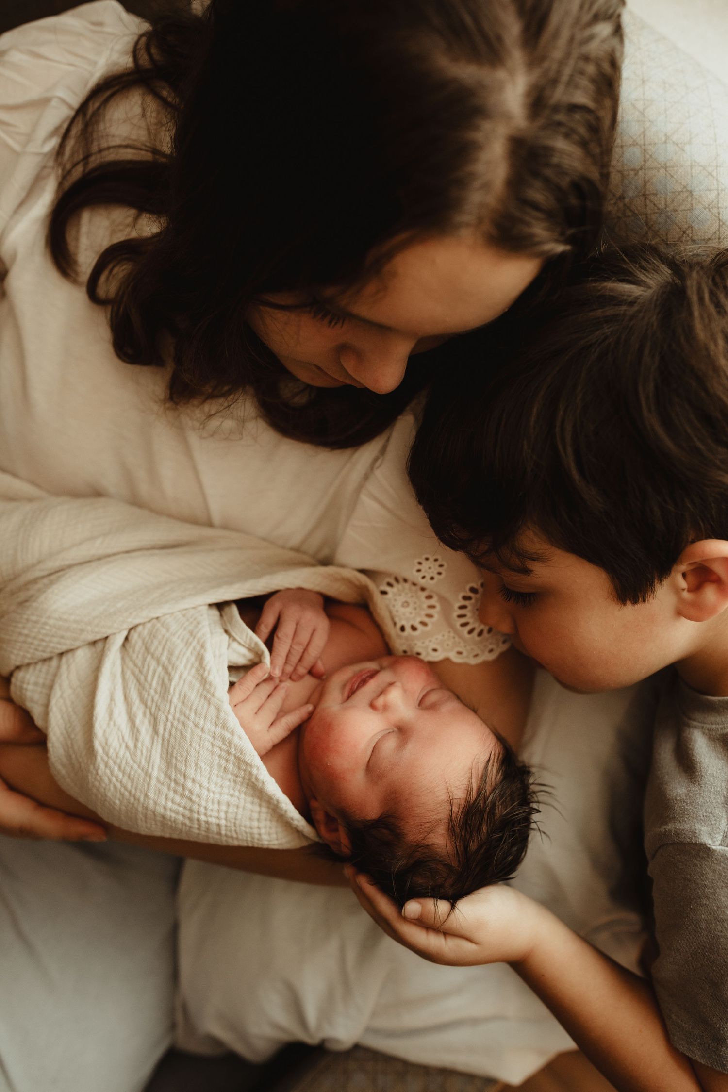 A loving mother gently kisses her sleeping baby in a tender sequence of black and white photographs.