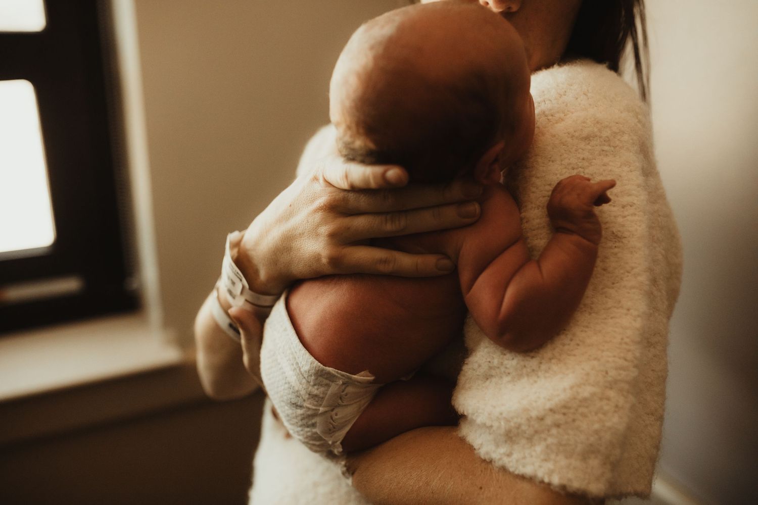 Series of close up shots showing a newborn baby's tiny fingers and hands being gently held in warm lighting.