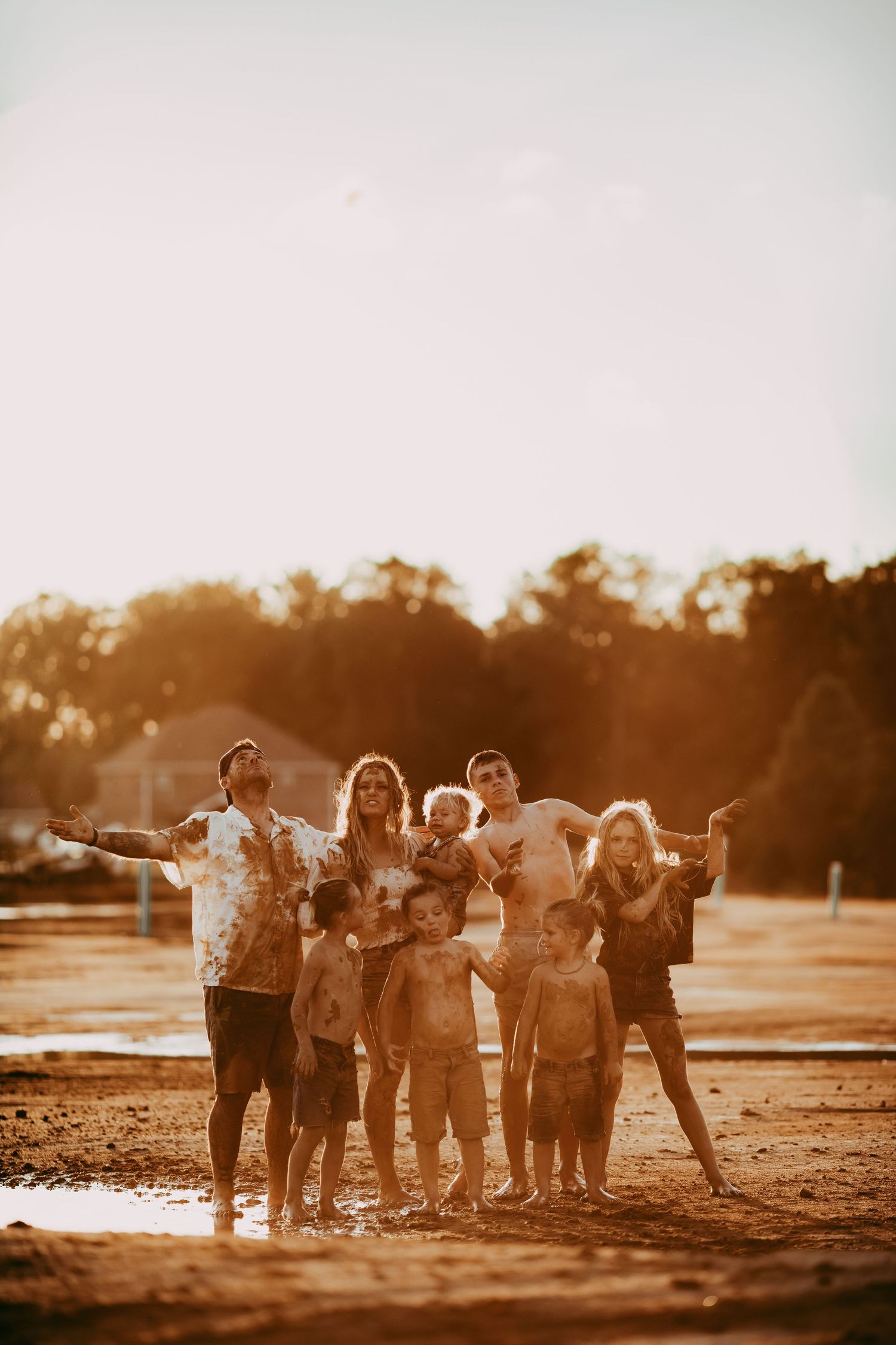 Group of people standing together on a beach at sunset, captured in a sepia-toned image with warm lighting.