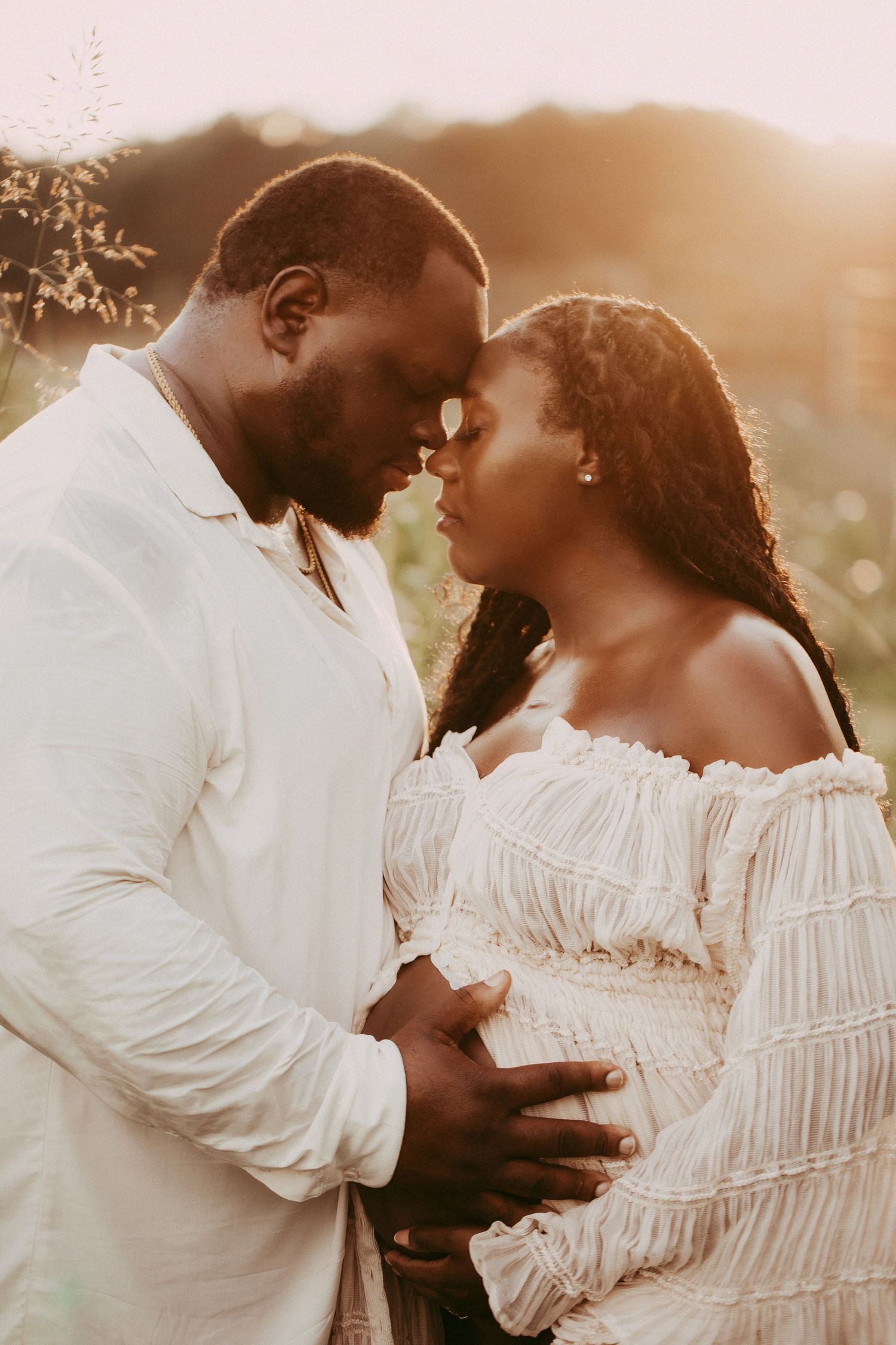 A couple embraces tenderly in a romantic sunset photoshoot sequence wearing white clothing.