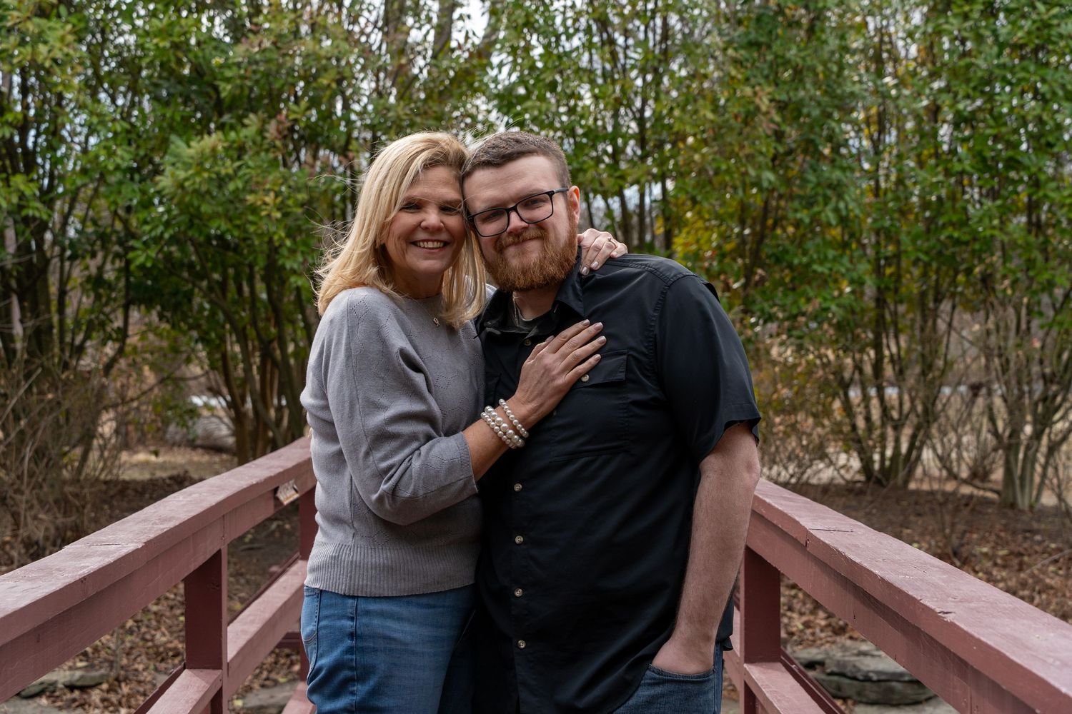 Mother and son embracing on a wooden bridge during an outdoor photoshoot.