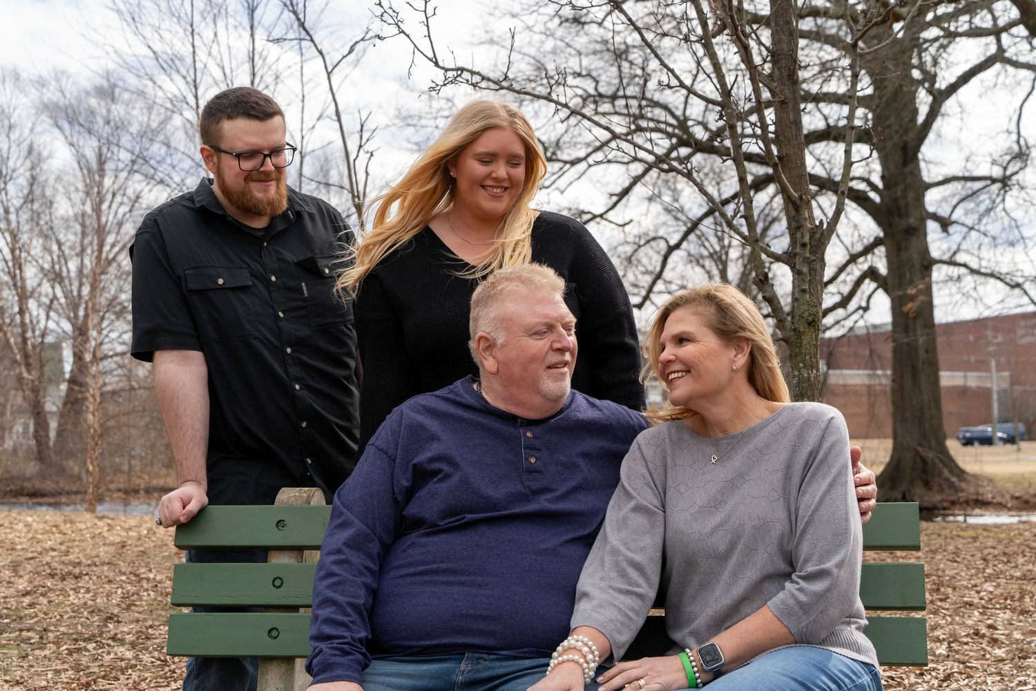 Family enjoying a relaxed moment together on a park bench during an outdoor photo session.