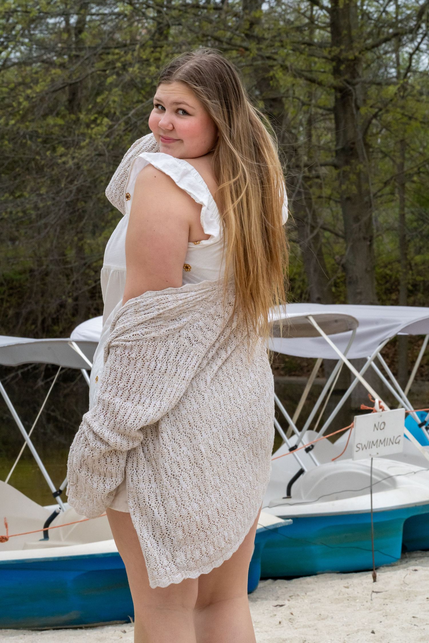A summertime portrait near boats with someone wearing a white textured dress.