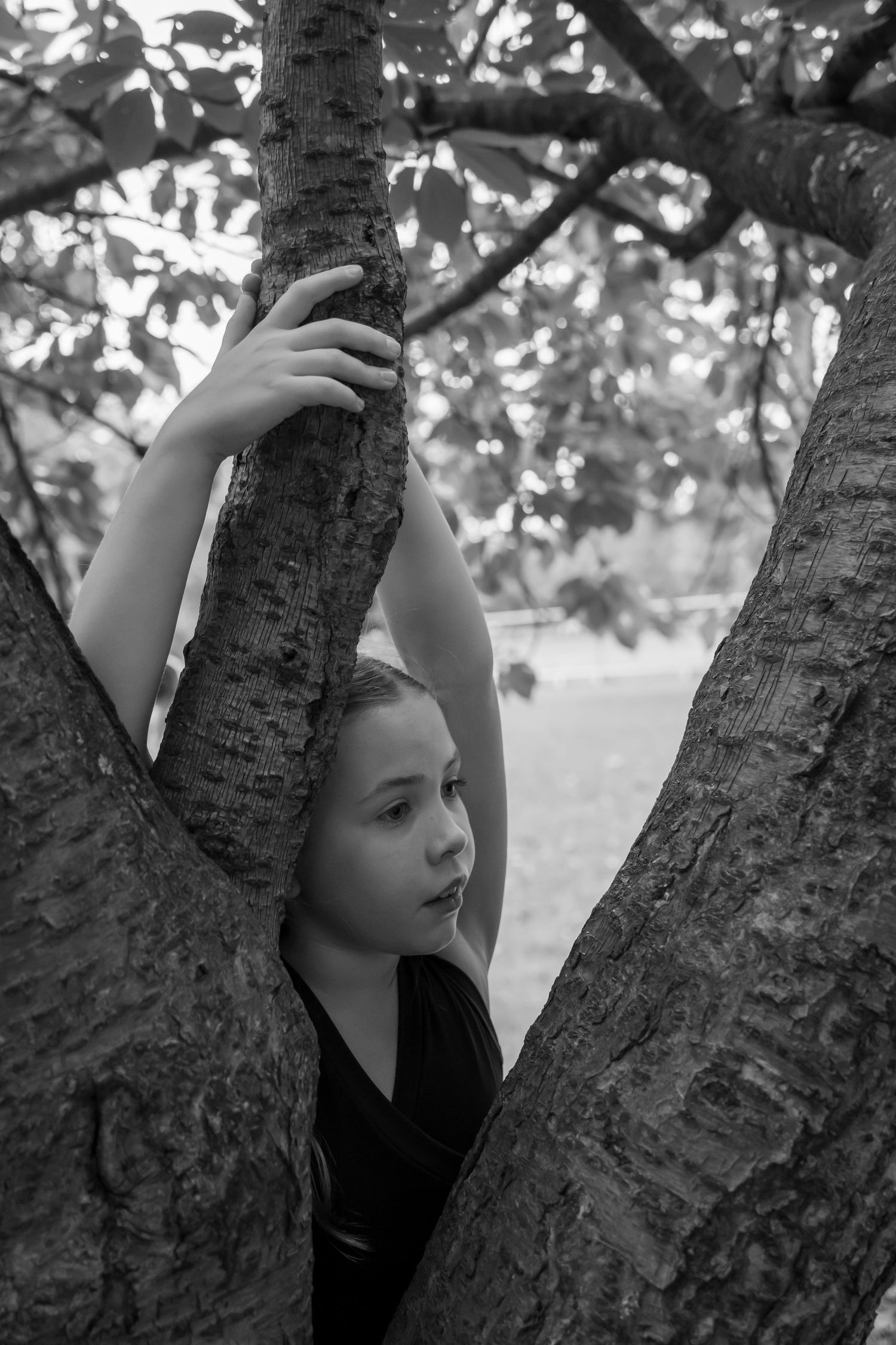 Artistic black and white close-up portrait pose against tree trunk texture.
