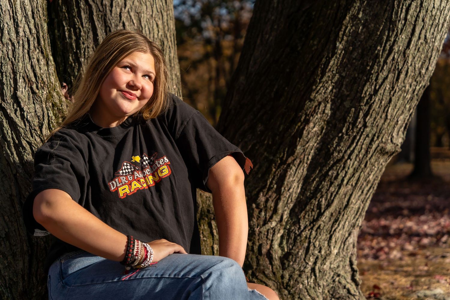 Casual outdoor portrait against a tree trunk in natural lighting.