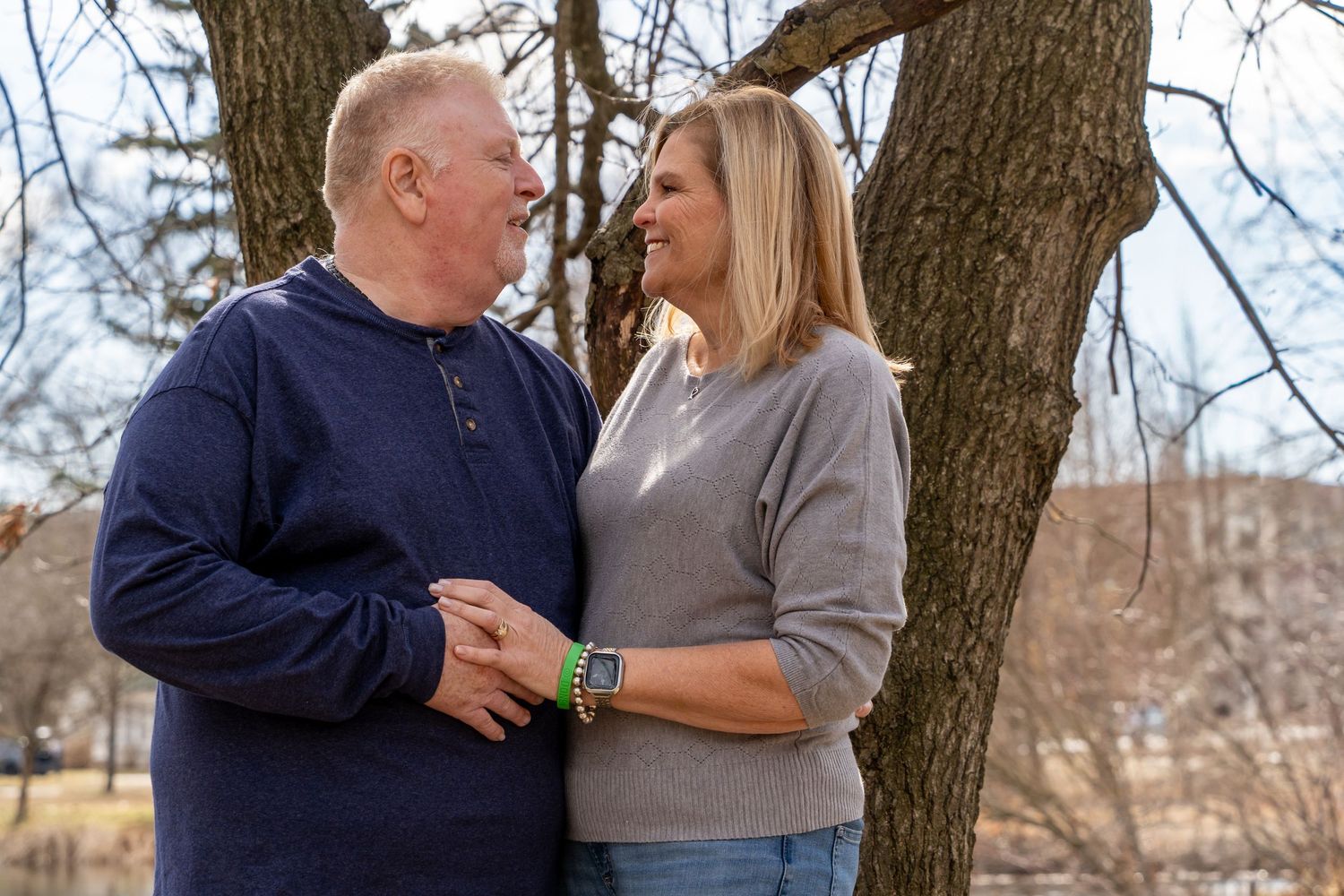 Couple sharing an intimate moment under a tree by a lake.