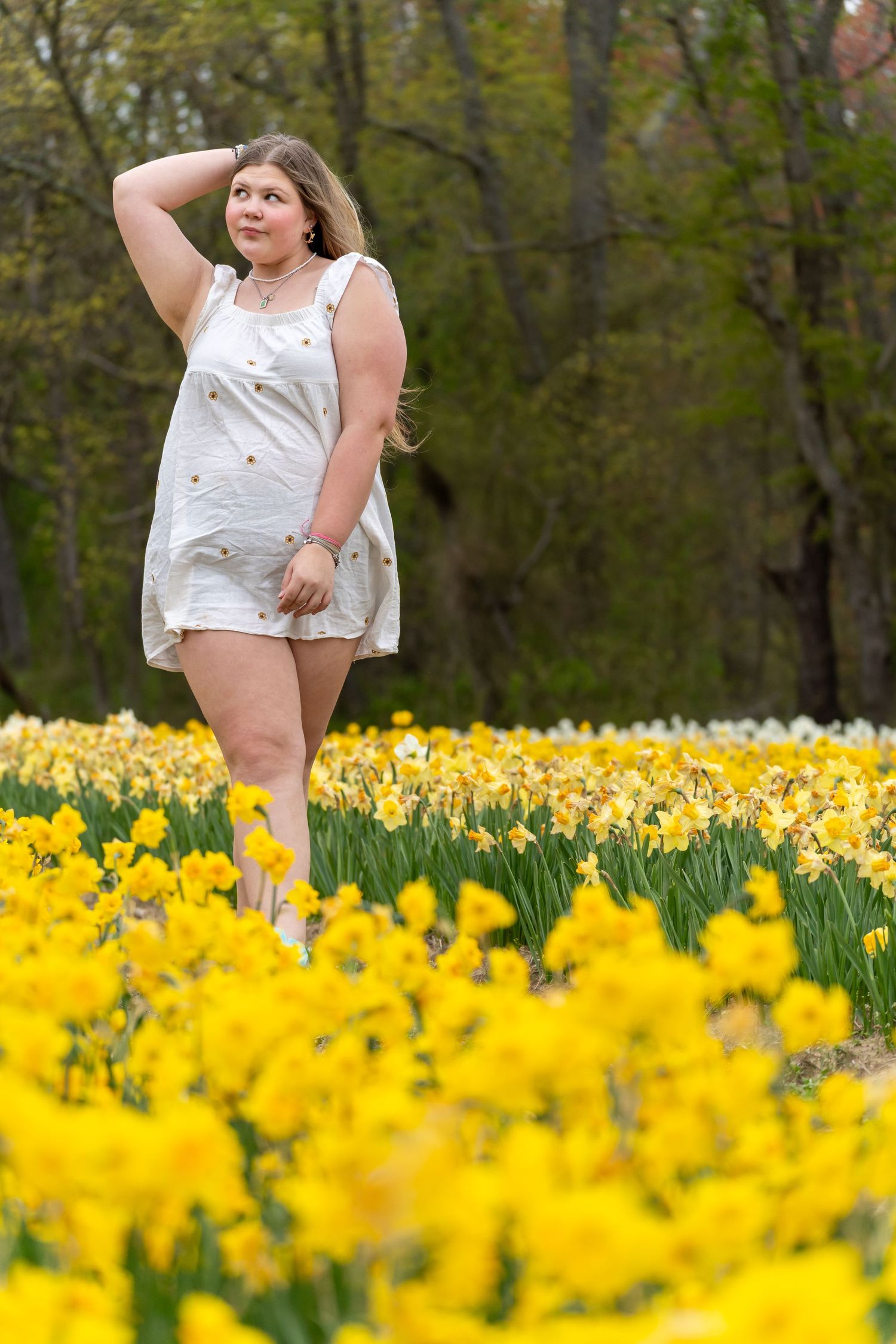 A springtime photoshoot in a field of bright yellow daffodils and greenery.