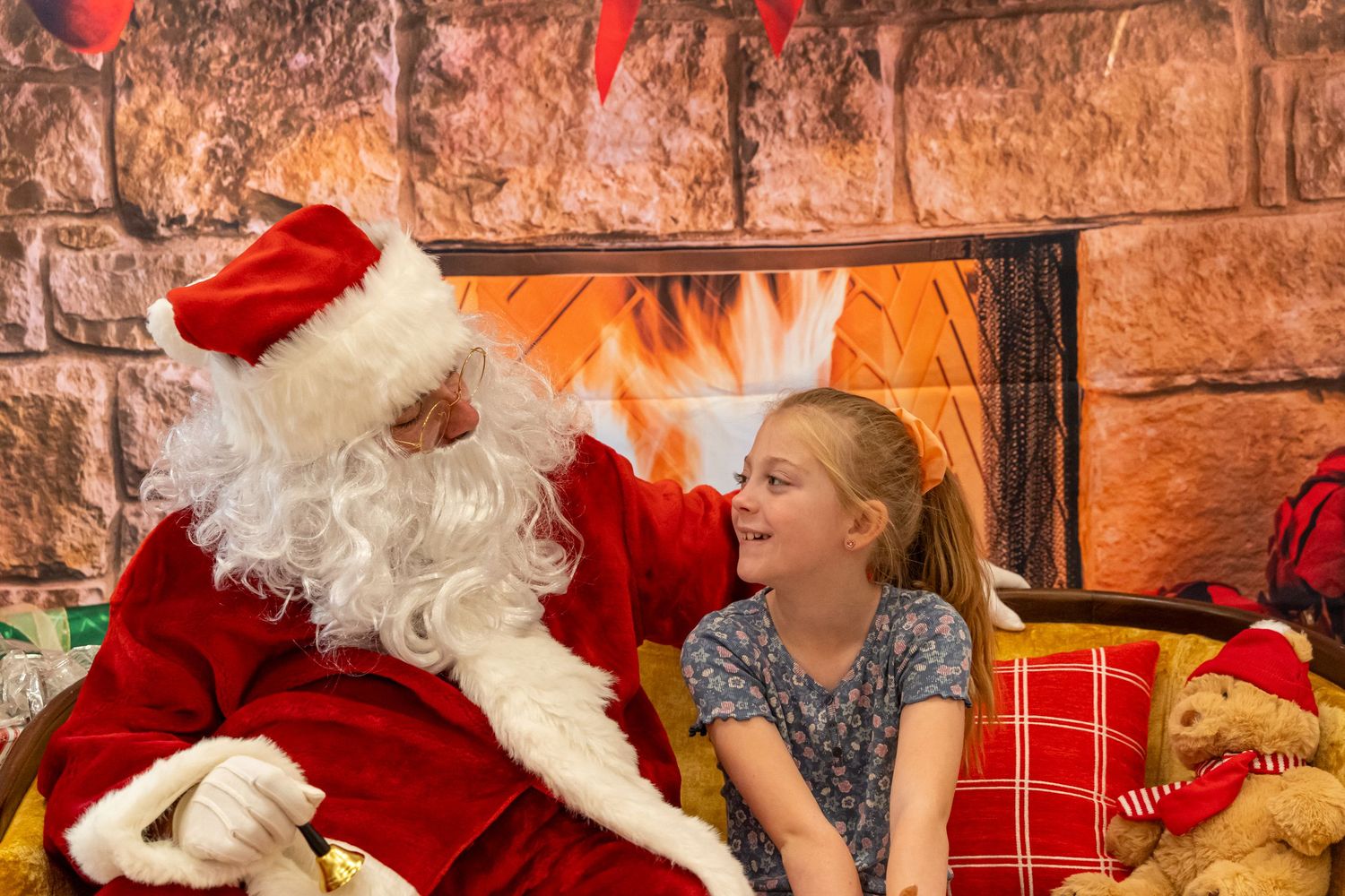 A cheerful holiday moment with Santa and a visitor engaged in animated conversation by the fireplace.