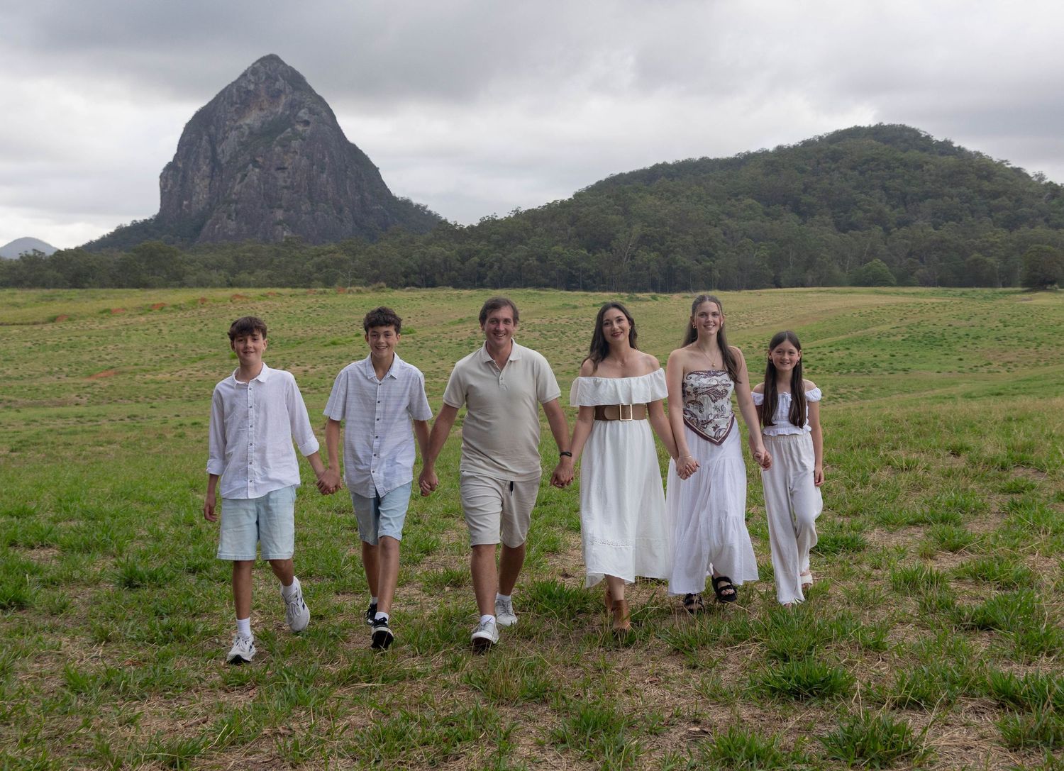A family walking towards the camera together holding hands.