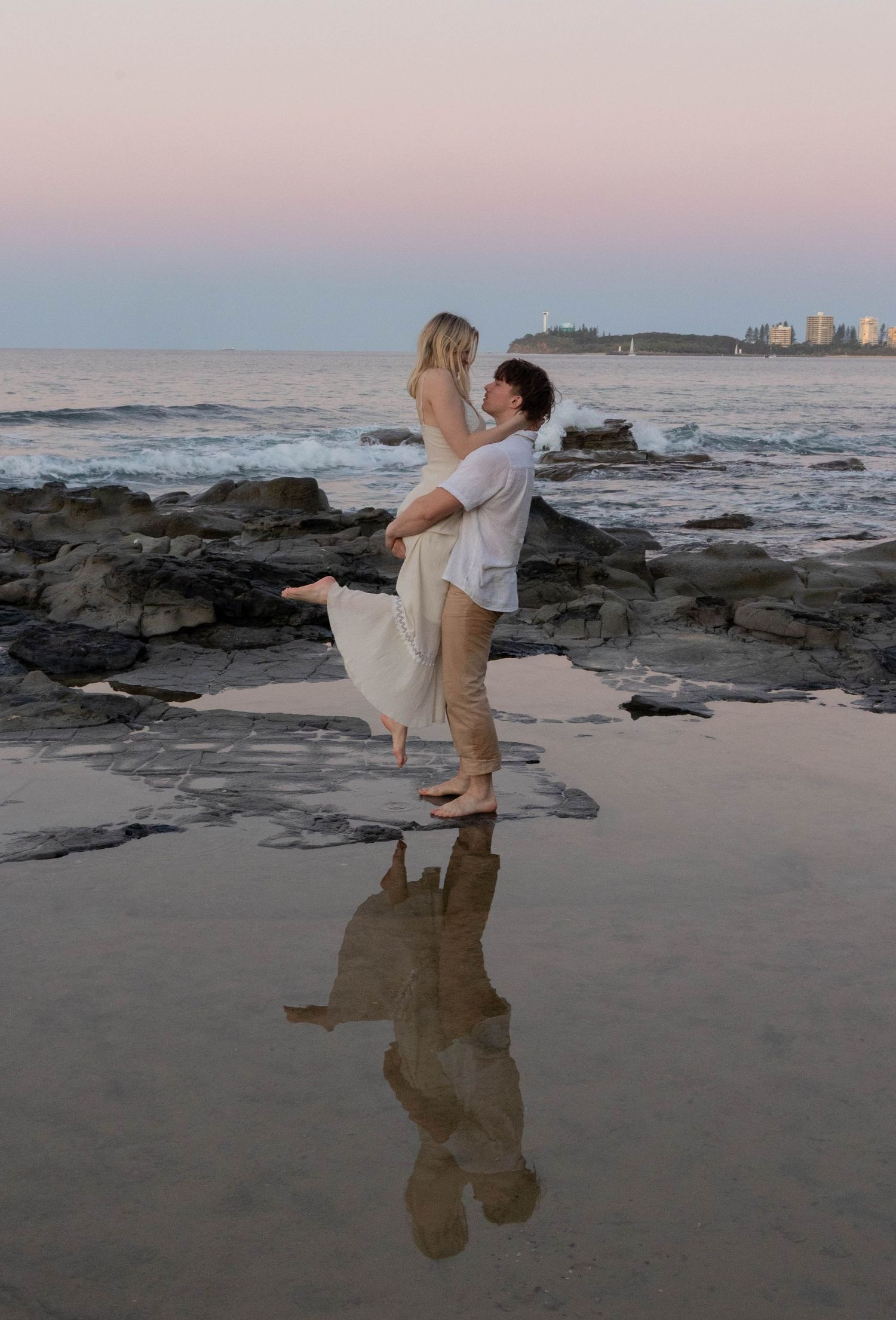 Shows a couple posing for their couple photos. He is picking her up.