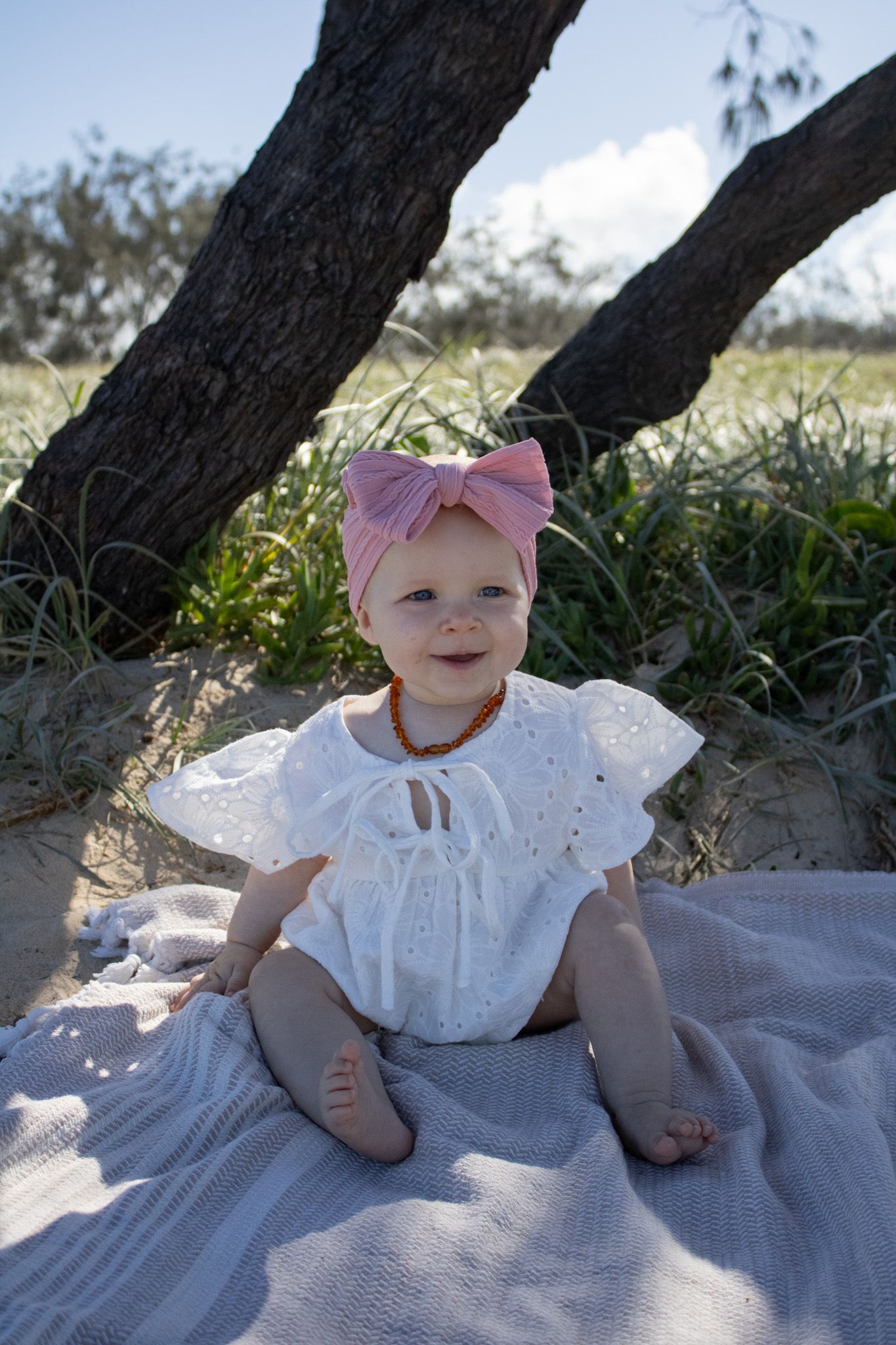 A photo of a baby sitting and looking curiously at the camera during a photoshoot.