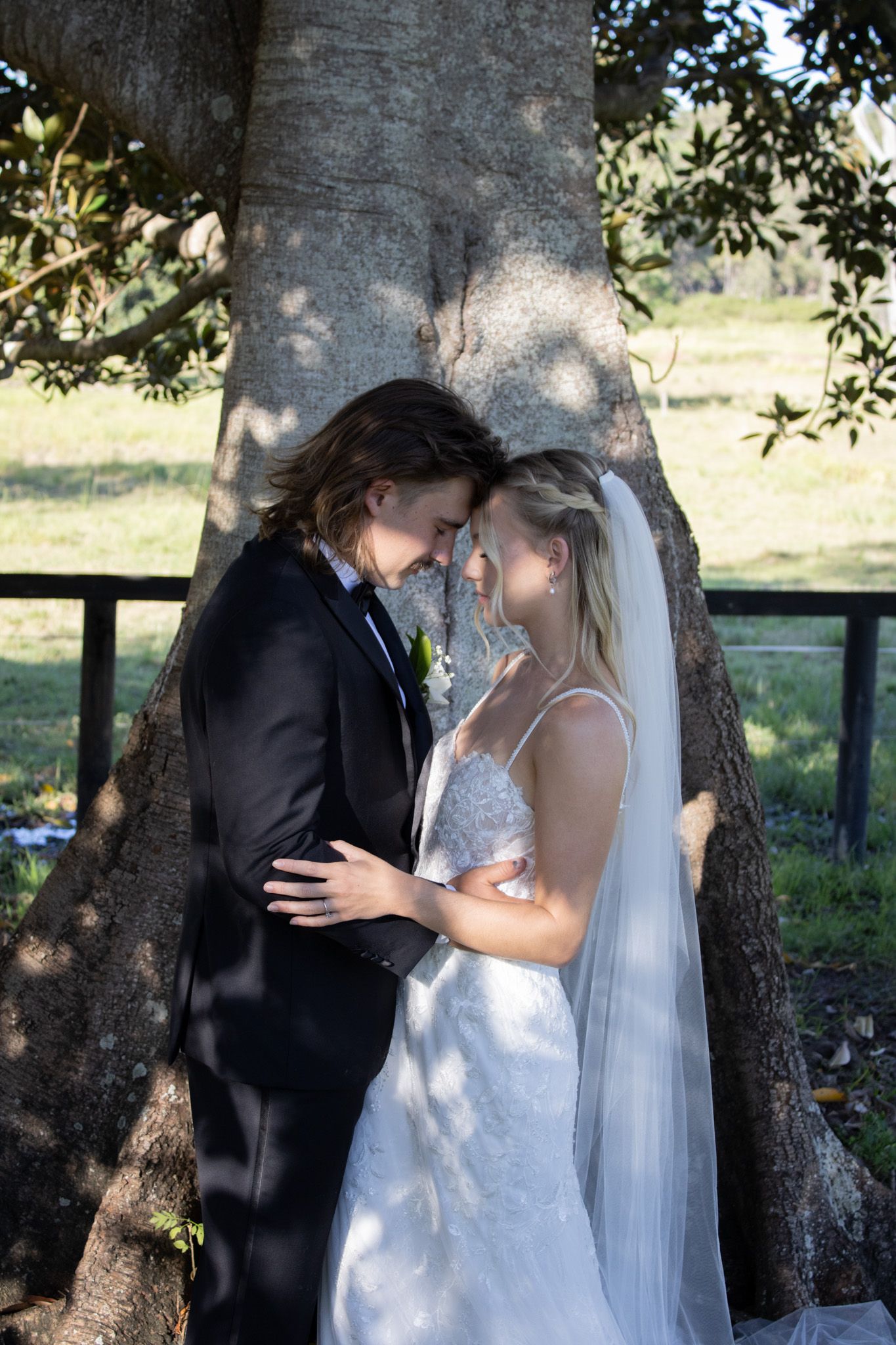 Newlywed couple getting photos under a tree.