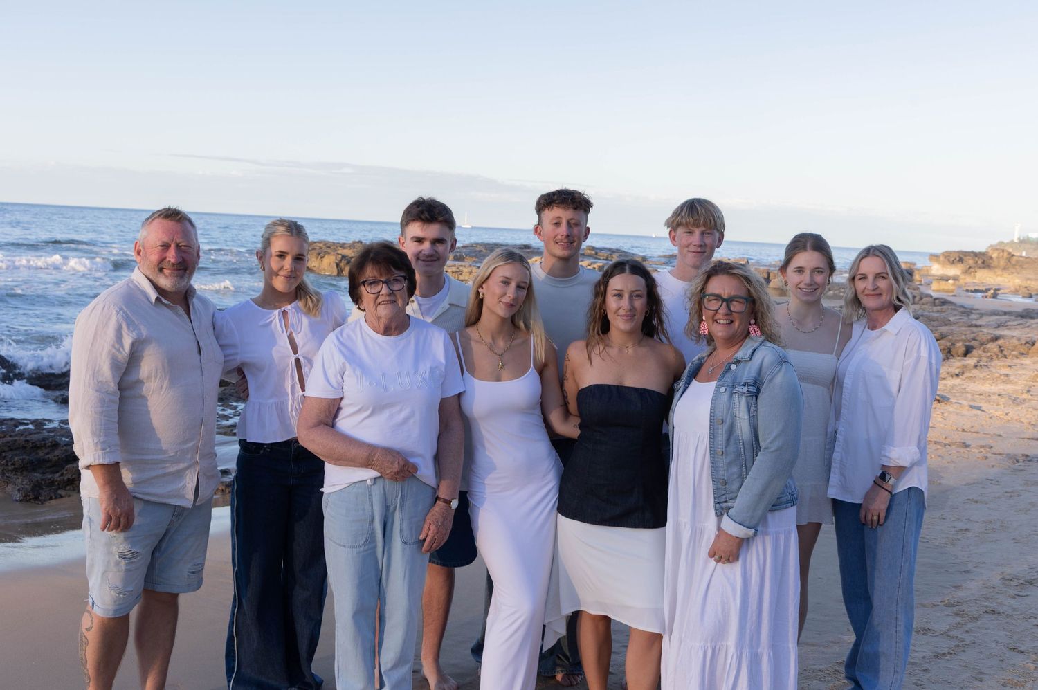 A photo of an extended family gathered together outdoors, smiling and enjoying time with one another during their photoshoot.