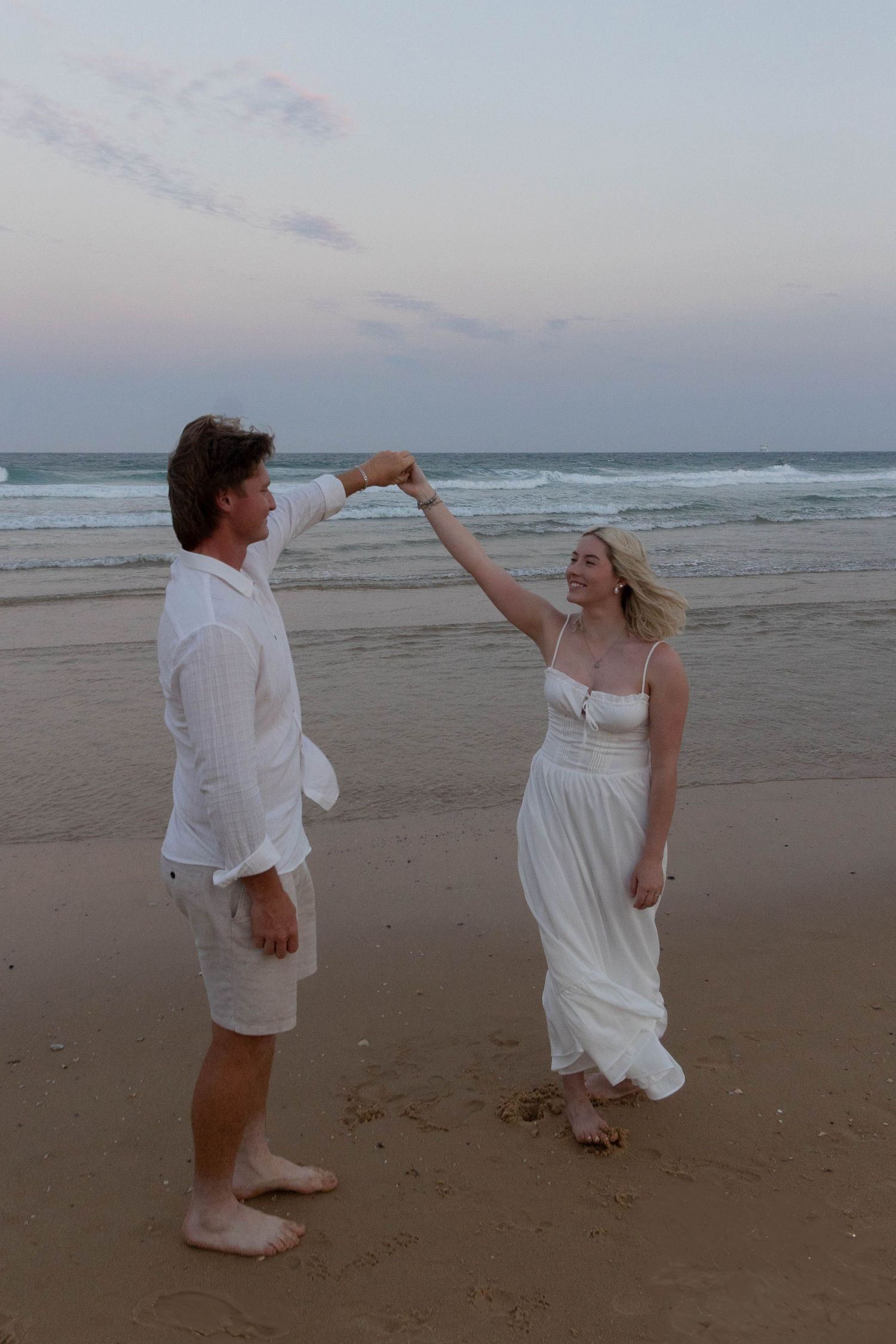 Couple dancing at the beach for their engagement photos.