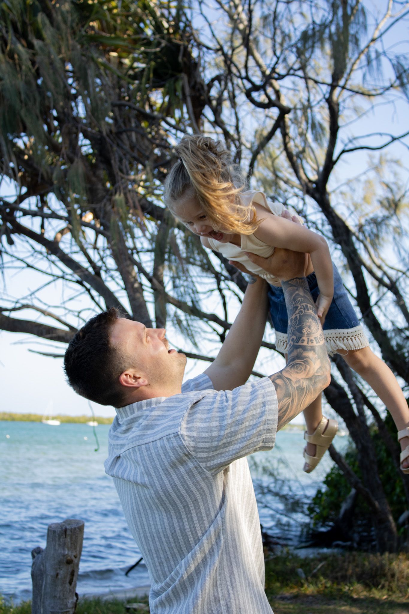 A photo of a dad and daughter playing and laughing together during their photoshoot.
