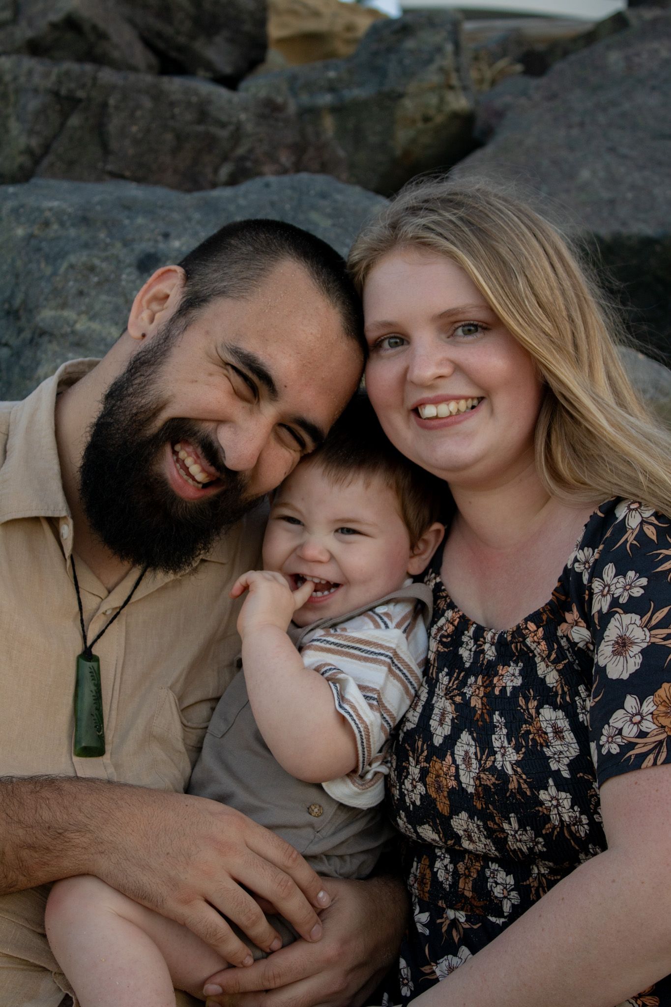 A photo of a family standing together outdoors, smiling and interacting naturally during their photoshoot.