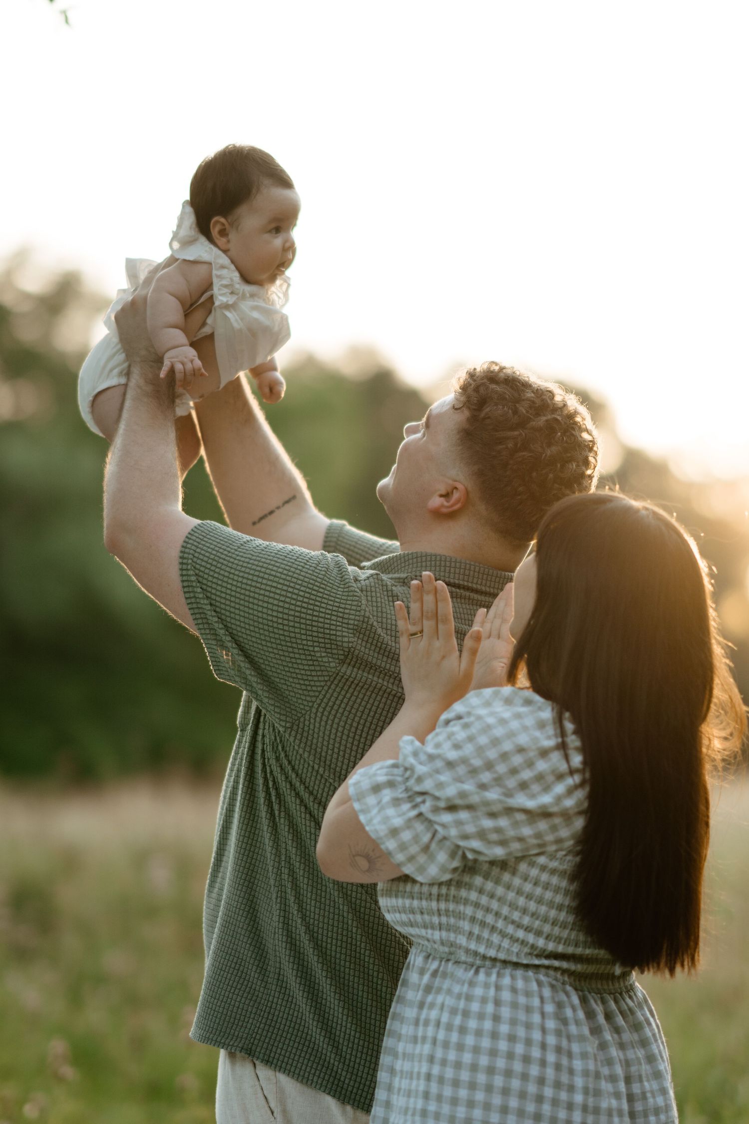 A family shares tender moments together in a sunlit field during golden hour.