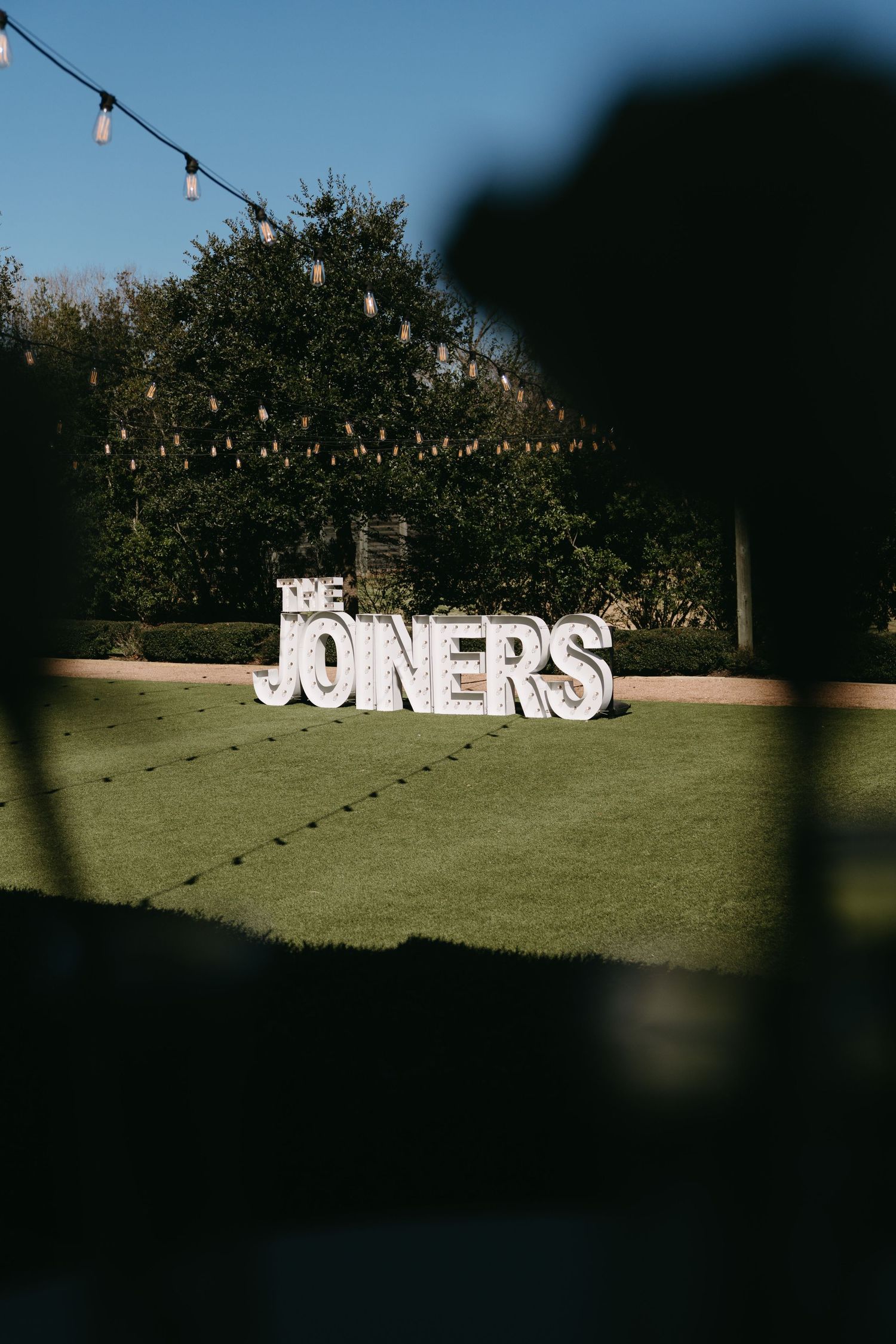 String lights illuminate a grassy field with large white letters spelling 'SOMERS' displayed across multiple frames.