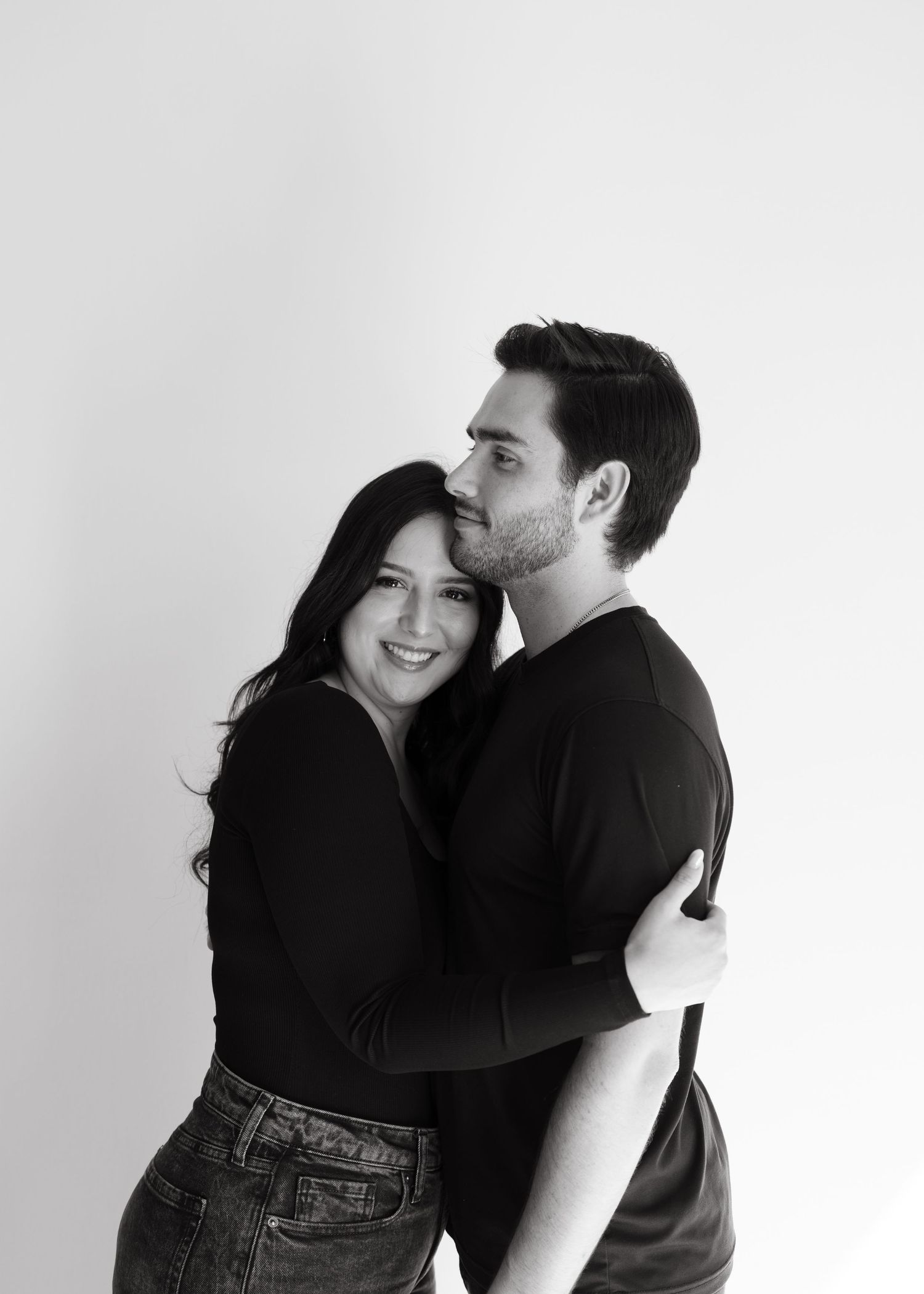 A couple embraces in a series of black and white romantic photos against a plain white background.