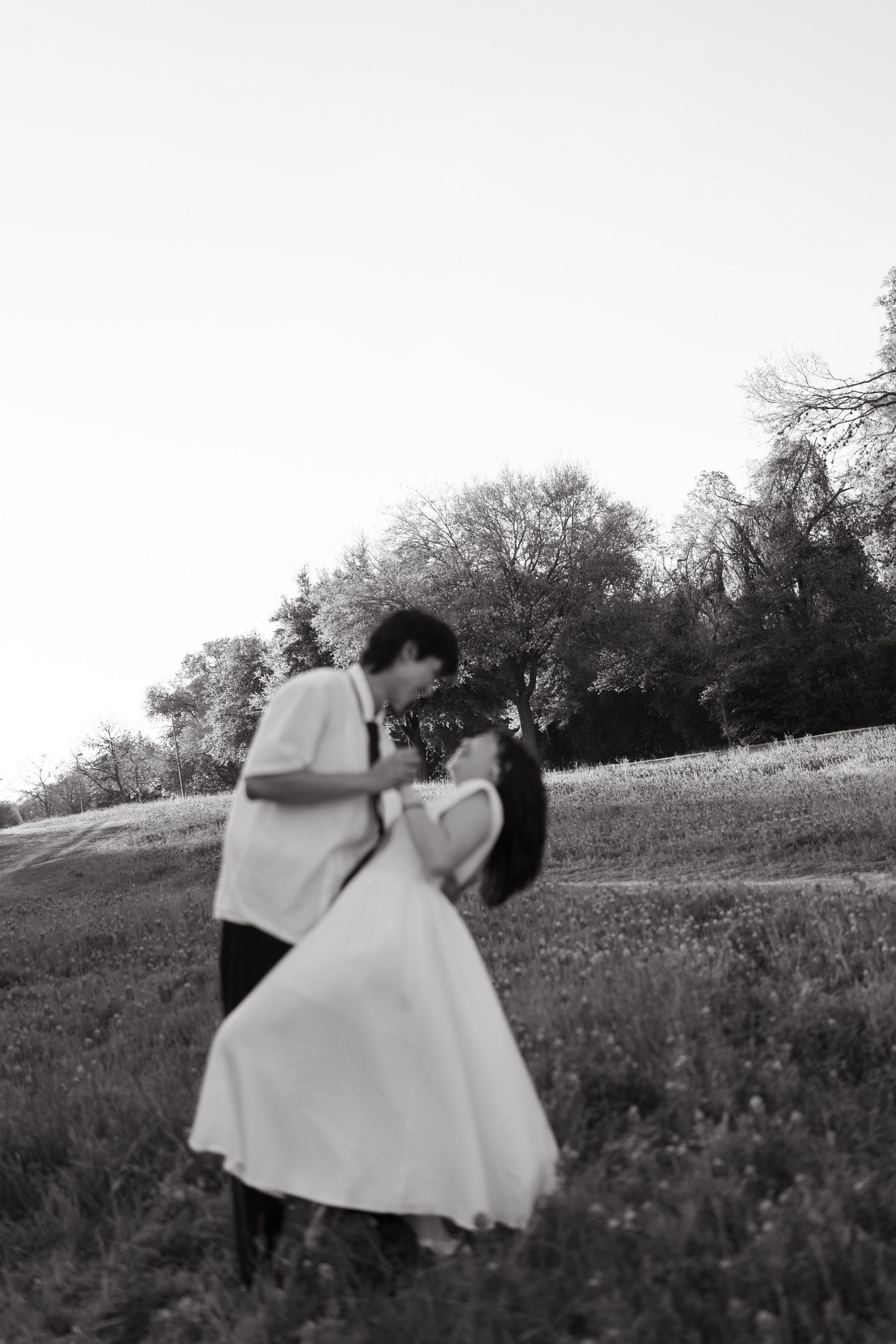 A sequence of black and white photos showing figures in white dresses dancing in a grassy field.