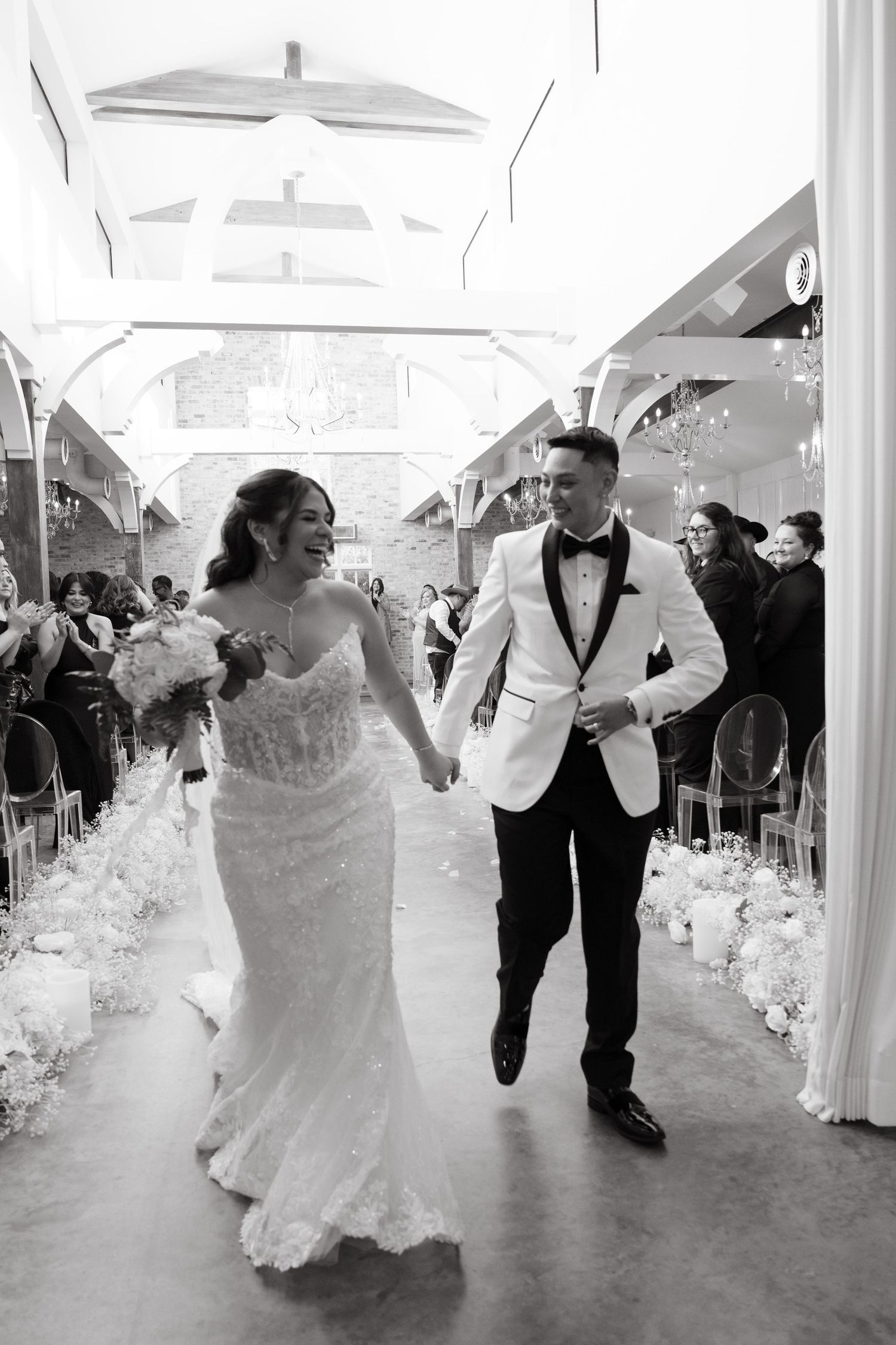 Couples dancing and twirling in formal wedding attire at an elegant reception venue decorated with white draping.
