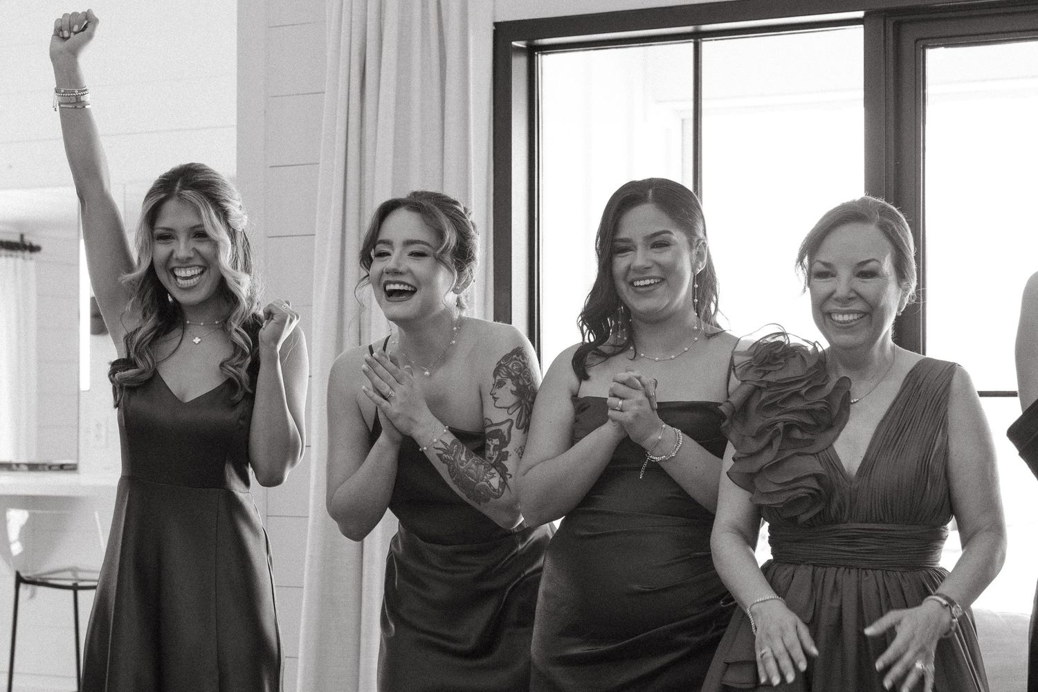 A group of people in black attire laugh and celebrate together during a joyful gathering.