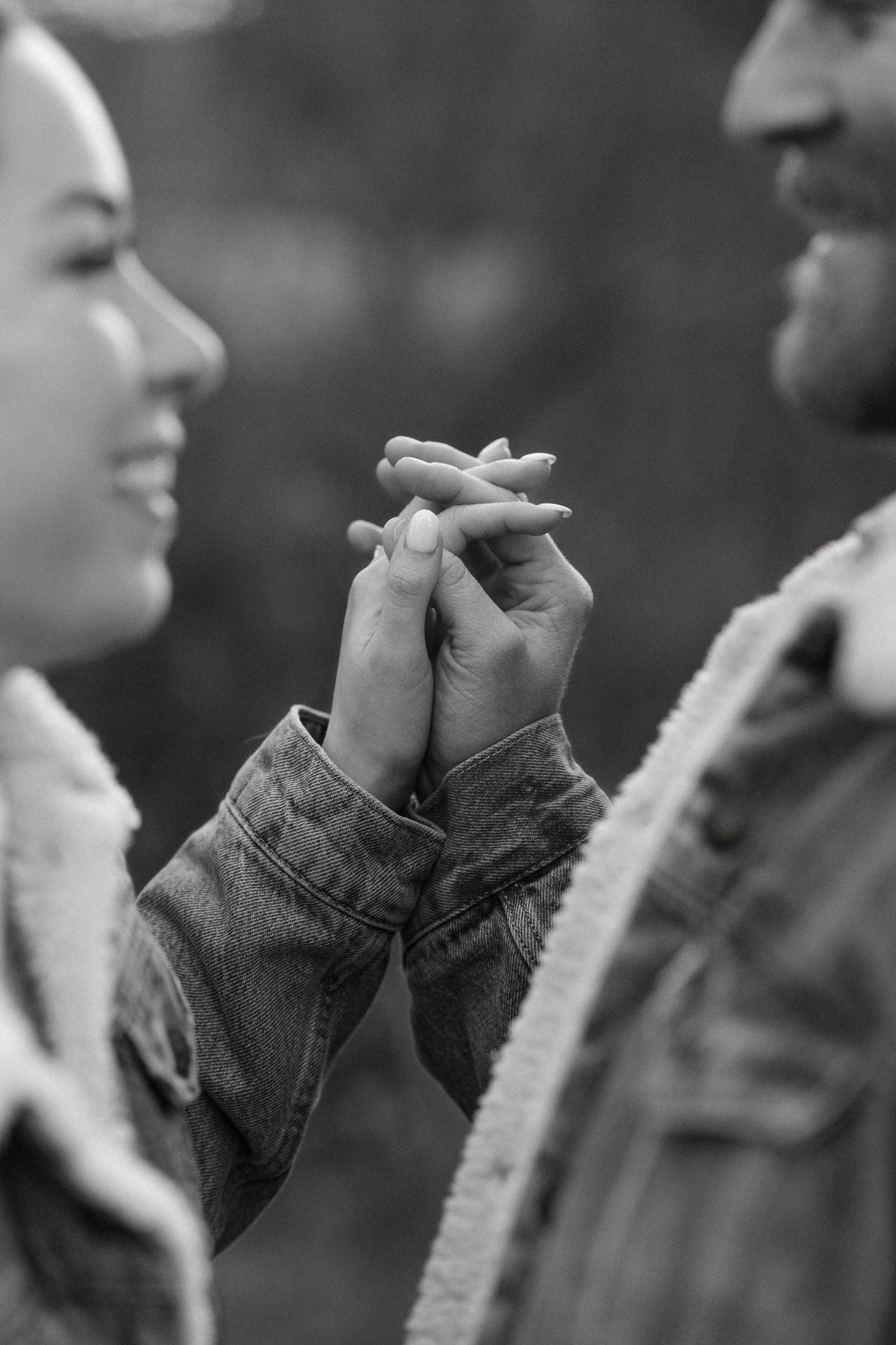 A black and white photo shows hands in denim jackets against a blurred background.