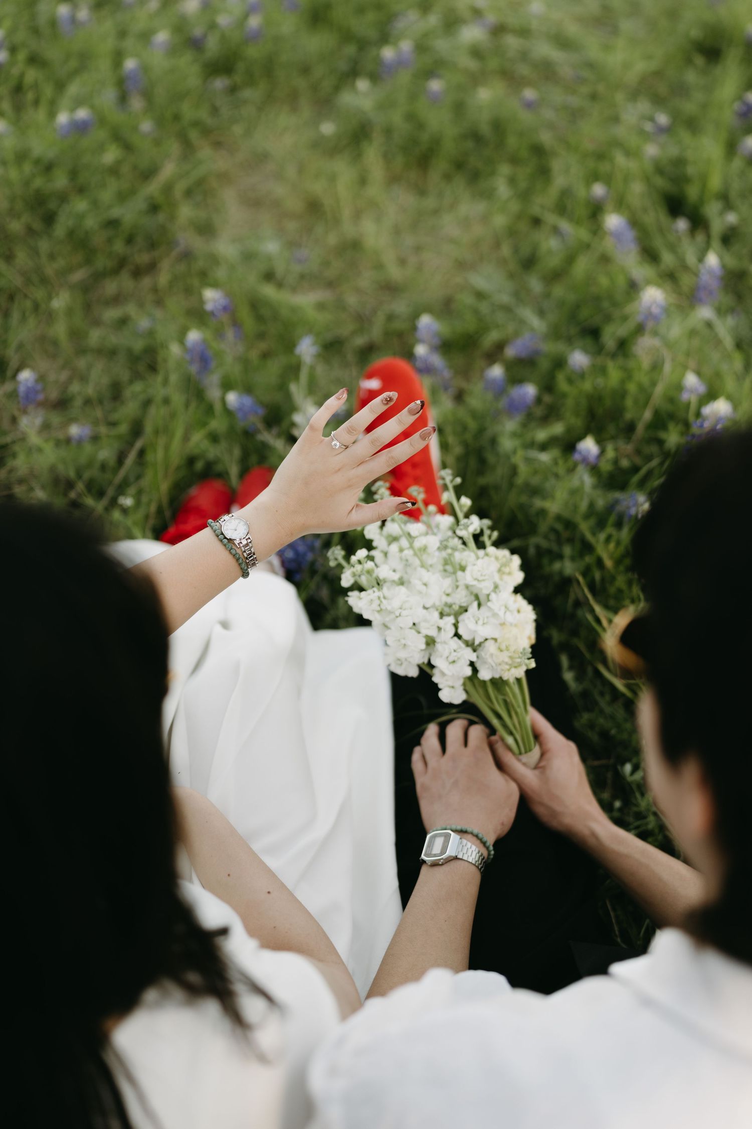 A series of four photos showing hands holding white flowers in a meadow with purple wildflowers.
