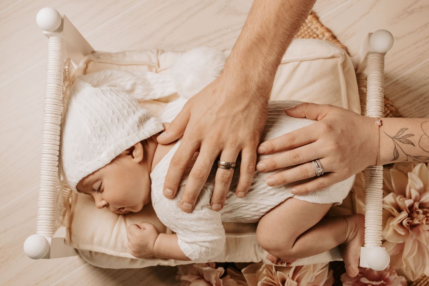 Gentle hands cradling newborn baby in white crib.