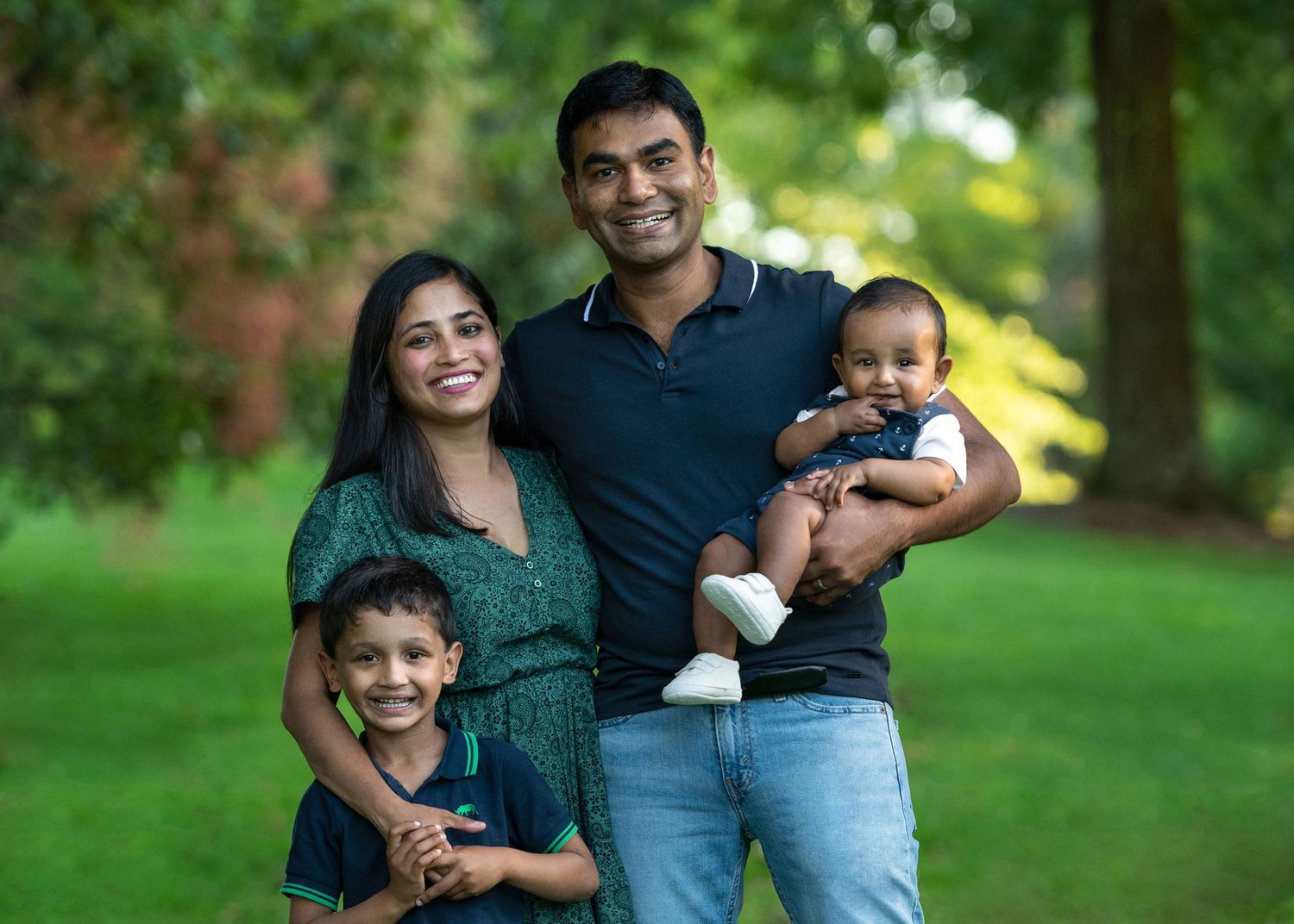 A family enjoys a candid moment together outdoors in a lush green park setting.