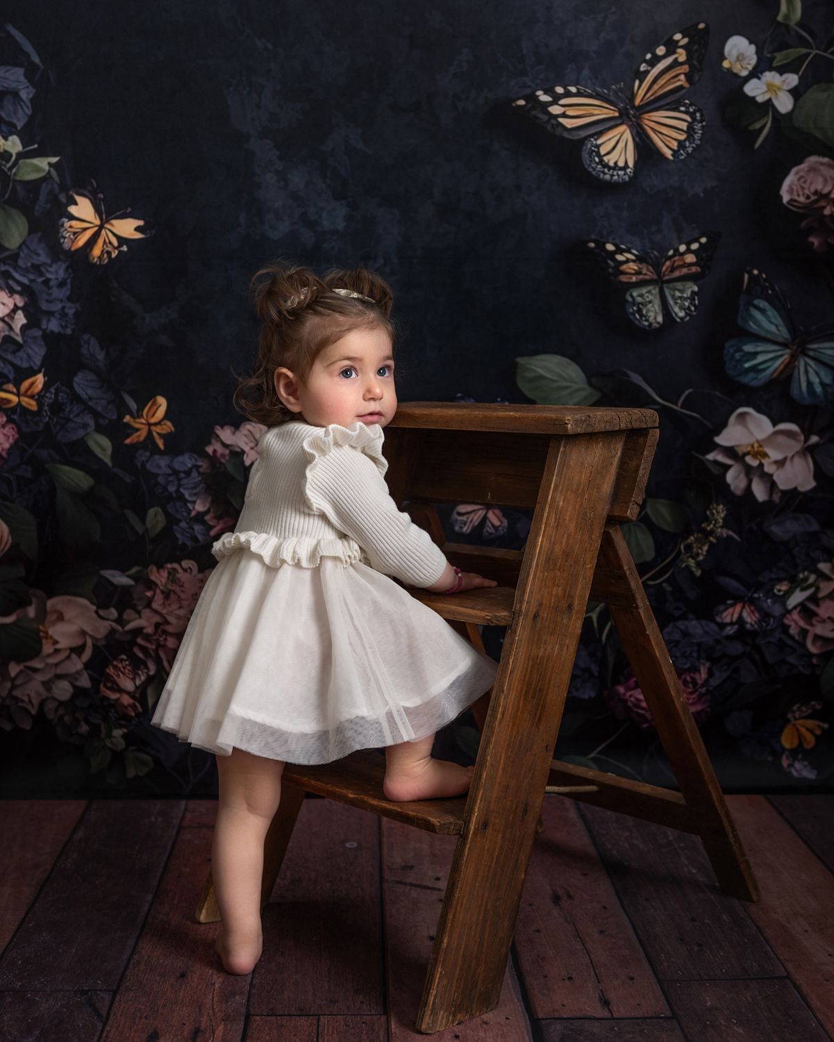 Rustic wooden floor with butterfly wallpaper backdrop in a vintage-style photo setting.