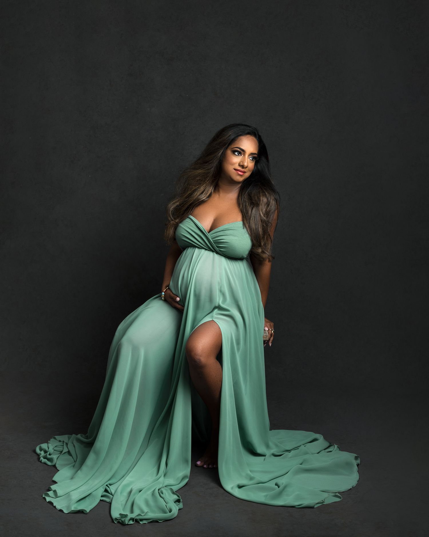 Mint green flowing dress creates graceful movement against dark studio backdrop.