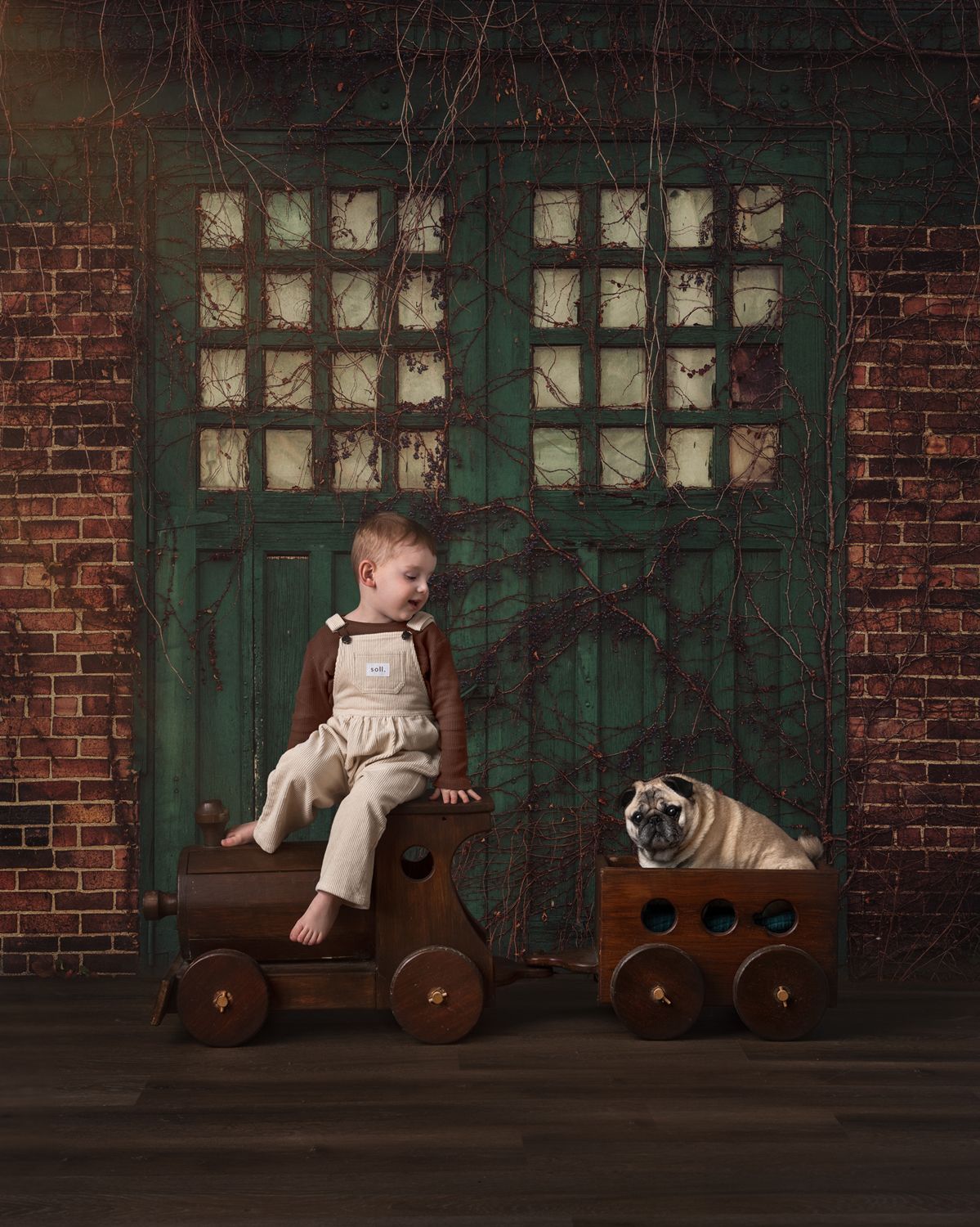 A vintage wooden toy train sits against a brick wall with glass block windows.