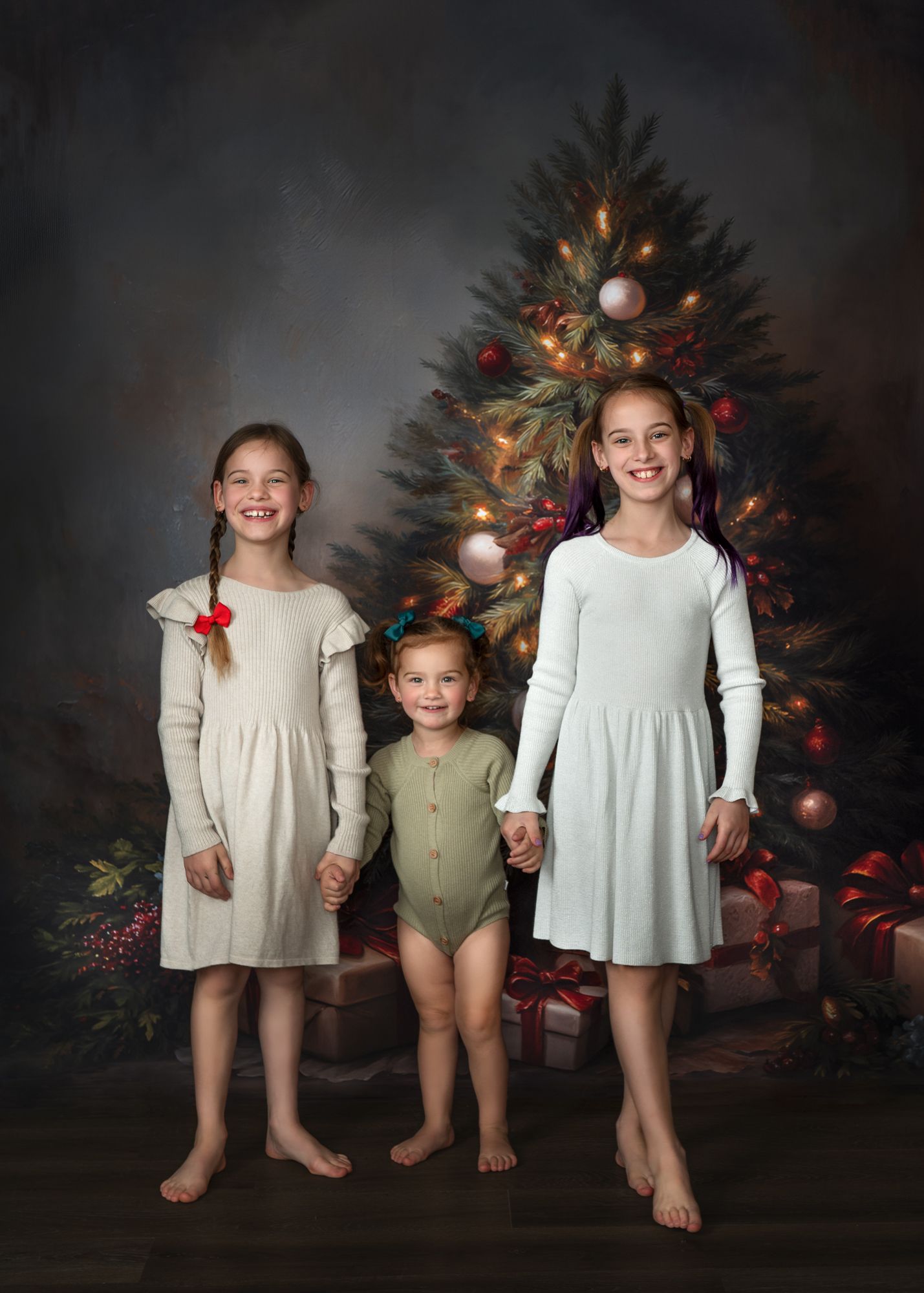 Children in white and sage green outfits pose in front of a decorated Christmas tree for a holiday photo session.