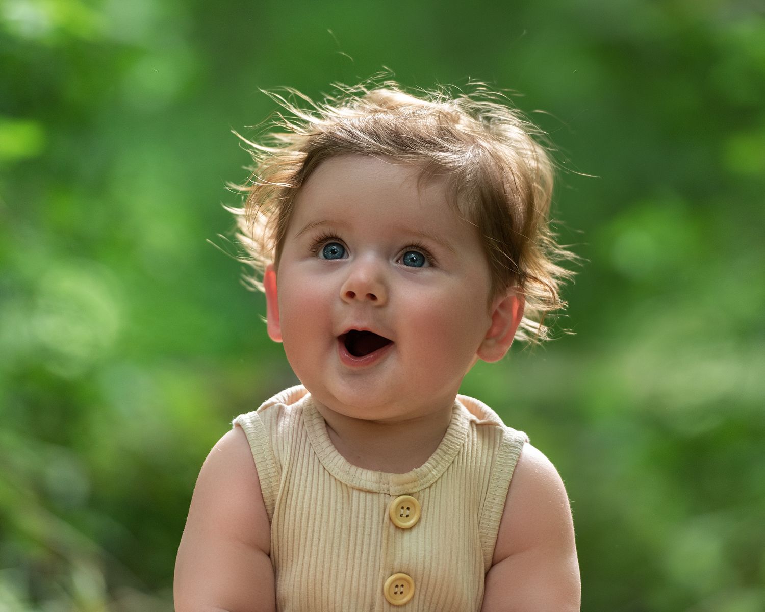 Close-up outdoor portrait with vibrant green foliage background.
