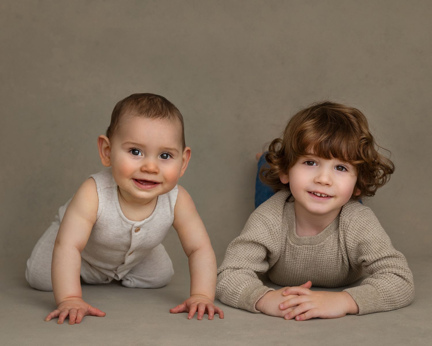 Studio portrait setup with subjects wearing coordinated gray outfits against neutral backdrop.